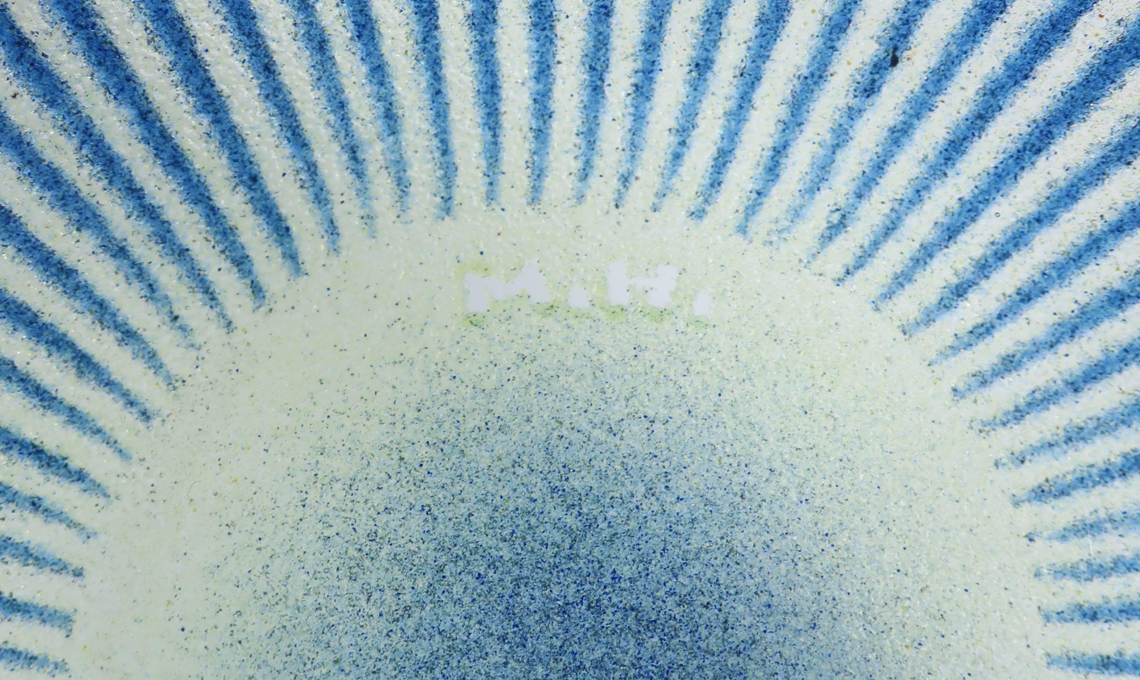 With an ovoid shape, this midcentury art glass bowl has a lovely pattern of blue lines radiating out from the yellow green centre. Signed by the artist with his trademark “M.H.” but undated, this bowl is in fantastic shape, with no chips, cracks, or