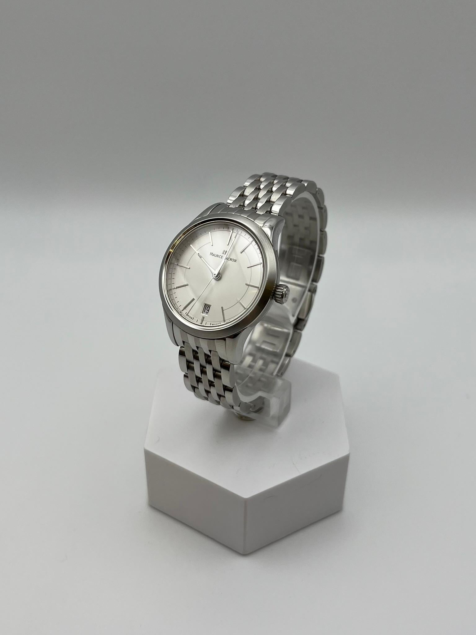 Eine raffinierte Maurice Lacroix Les Classique Uhr aus Stahl, die perfekte Synthese aus Schweizer Eleganz und Präzision. Das weiße Zifferblatt mit einem Durchmesser von 34 mm ist minimalistisch, mit schlanken Indexen und der Datumsanzeige bei 6 Uhr,