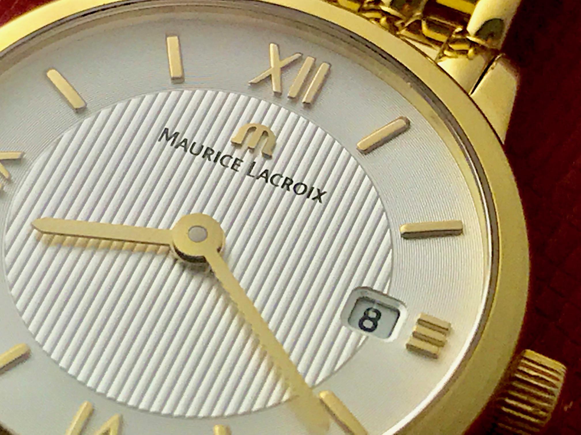 This elegant Ladies Maurice Lacroix features a white dial with yellow gold hour markers and Roman numerals. The dial also has a beautiful vertical line design integrated into the center of the dial, stretching to the hour markers. The case is made