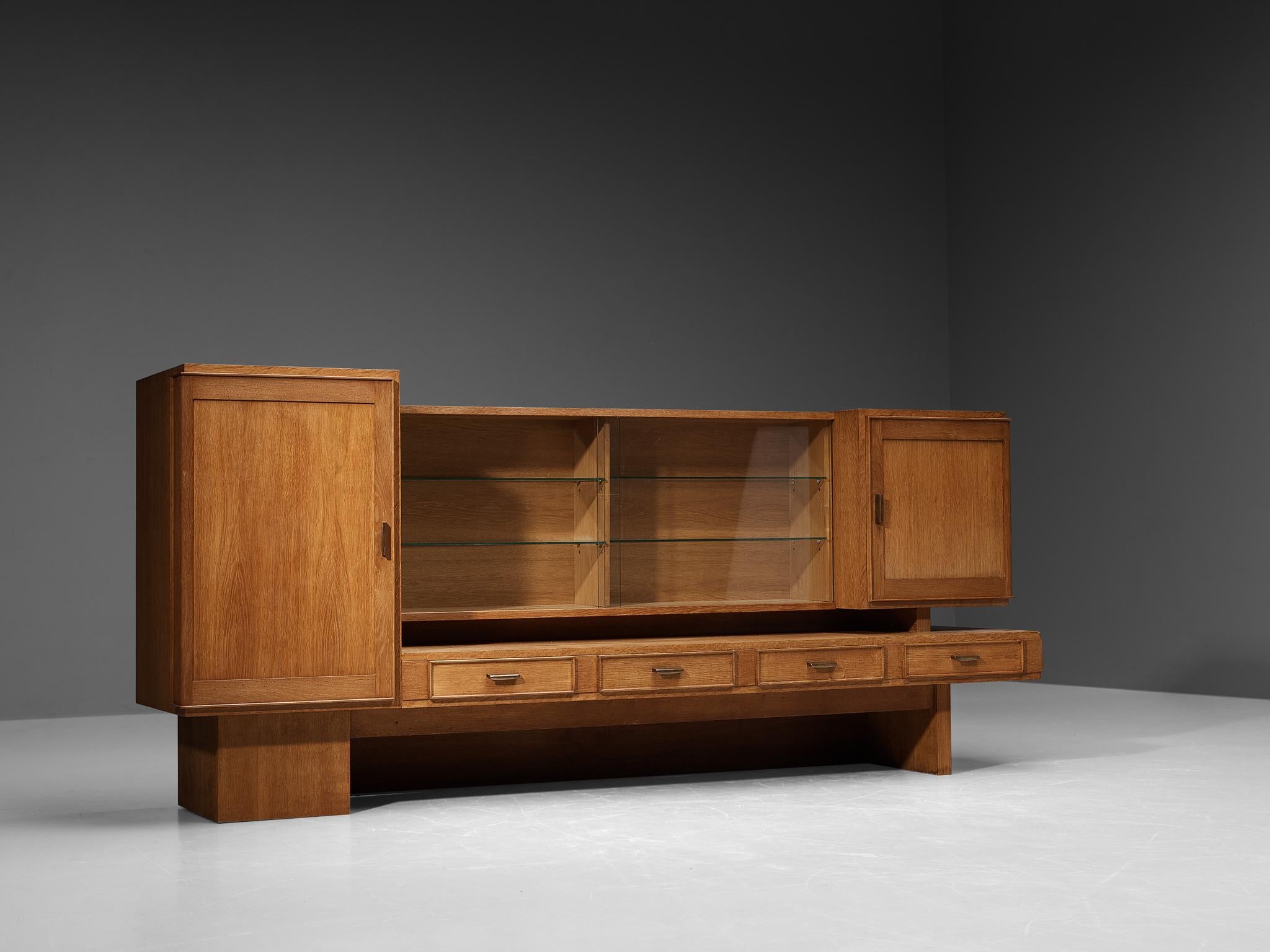 Maurice Pré, cabinet, oak, brass, glass, France, 1950s

This exquisite highboard in solid oak is designed by the French designer Maurice Pré (1908-1988) in the 1950s. It features a variety of different cabinets; two closed cabinets on both ends