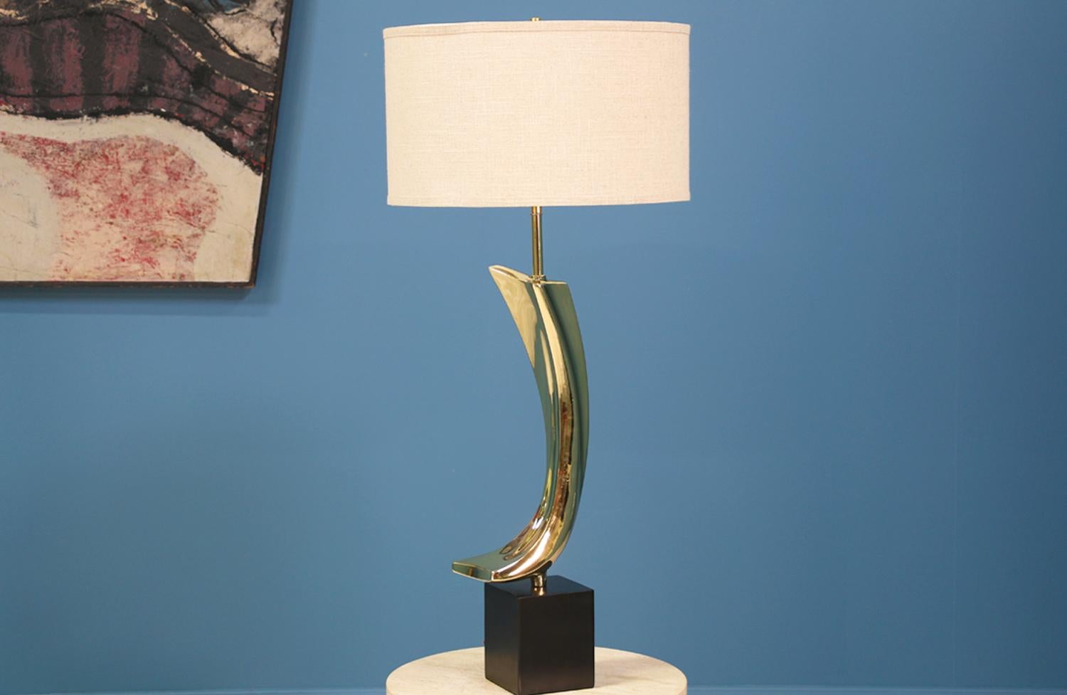 Table lamp designed by Maurizio Tempestini and manufactured in the United States by Laurel Light Co. in the 1960's. This unique lamp features a swooping sculptural brass body that has been polished and sits on a rectangular black lacquered base.