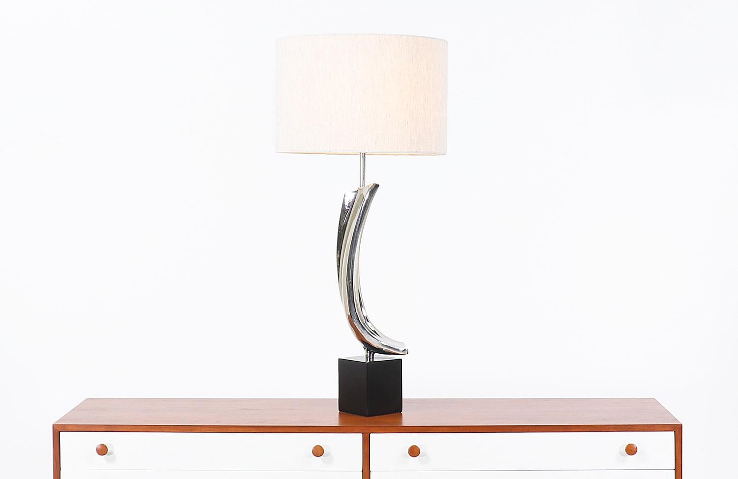 Modern table lamp designed by Richard Barr and Harold Weiss for Laurel Lamp Co. in the United States, circa 1960s. This unique table lamp features a swooping sculptural nickel-plated chrome body that sits on a rectangular black metal base exhibiting