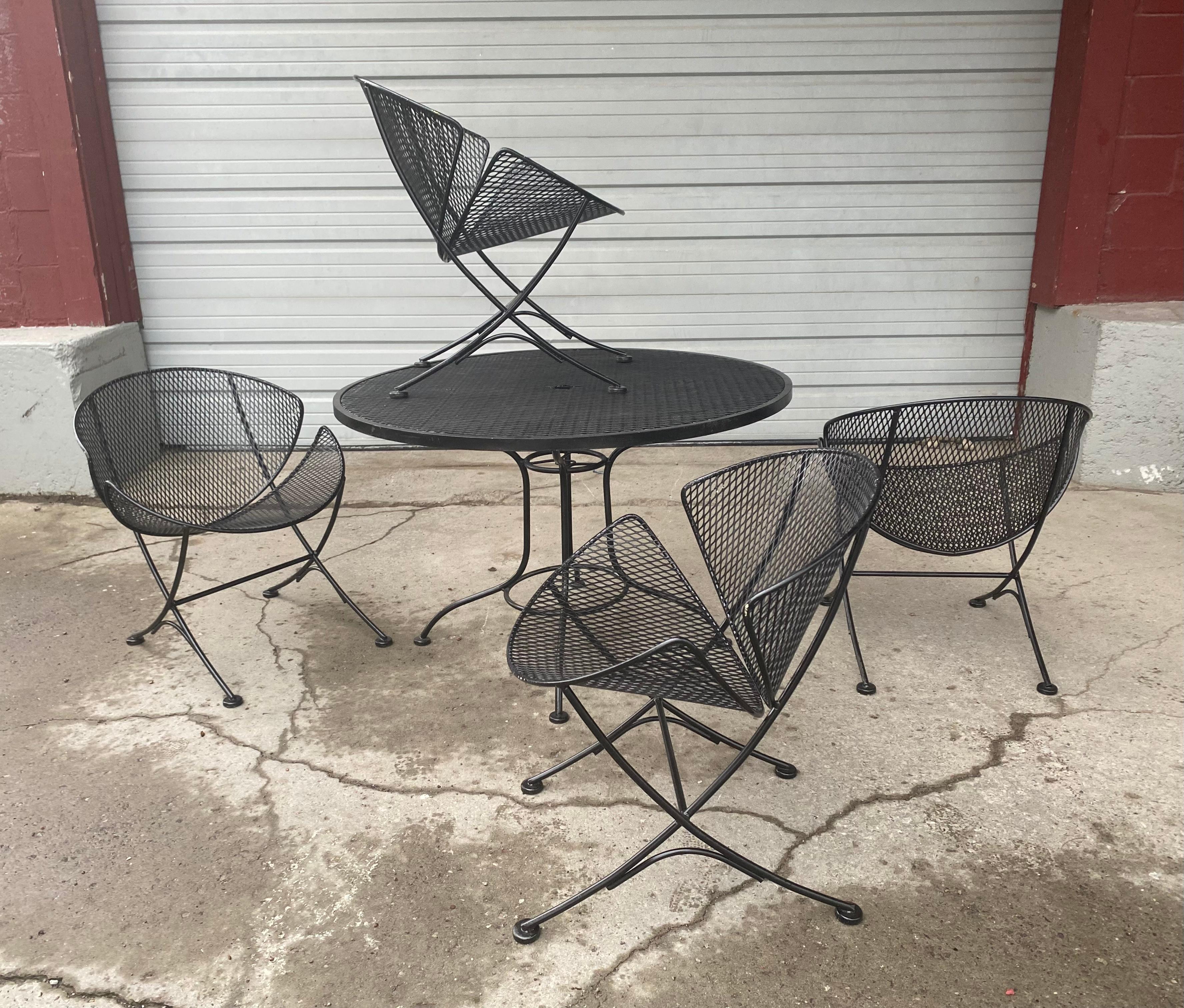 Classic Mid-Century Modern wrought iron patio / garden set, Dinette, designed by Maurizio Tempestini for Salterini. Set includes 4 matching Clam Shell chairs and Table, Dimensions Chairs: H 26.5 in. W 22.5 in. D 24 in., Table: H 26 in. Diameter 41 i