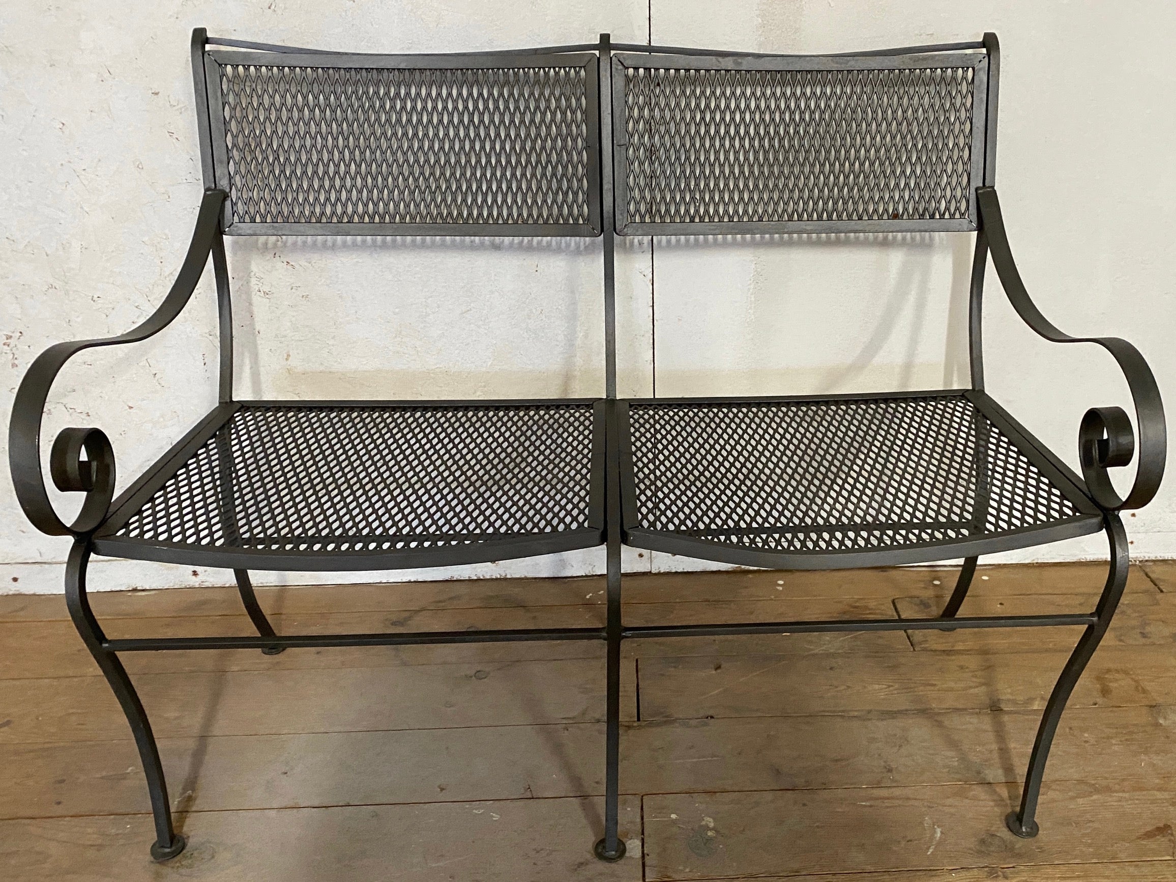 In the style of Maurizio Tempestini this black painted wrought iron framed and iron mesh outdoor loveseat will make a wonderful addition to any garden, porch or veranda.. Minimalist design with open arms and linear form, iron mesh seat and back flow