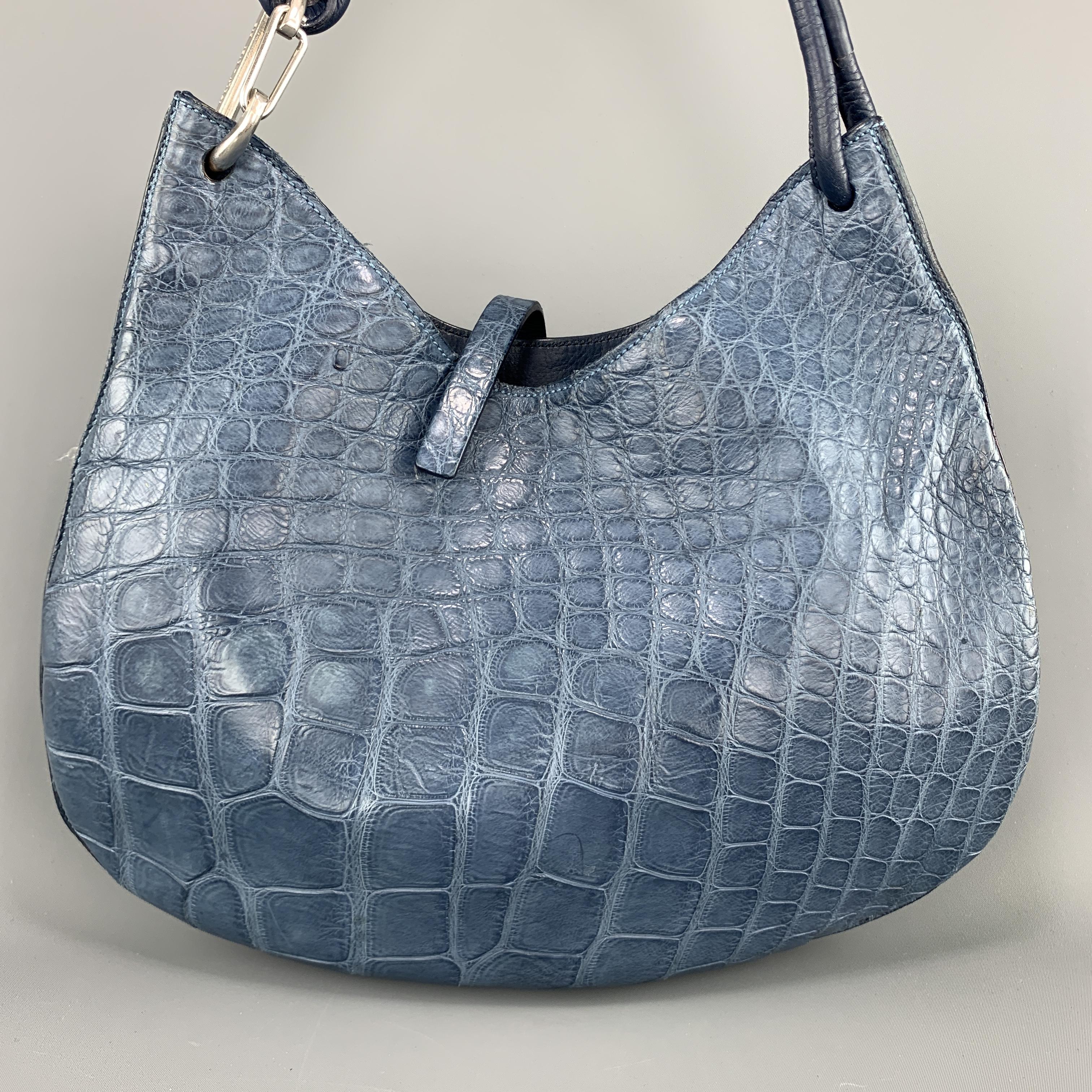 MAURO GOVERNA shoulder bag comes in blue alligator leather with a top strap, suede liner, and knitted shoulder strap with silver tone hardware clip detail. 

Very Good Pre-Owned Condition.

Measurements:

Length: 14.5 in.
Width: 1.5 in.
Height:
