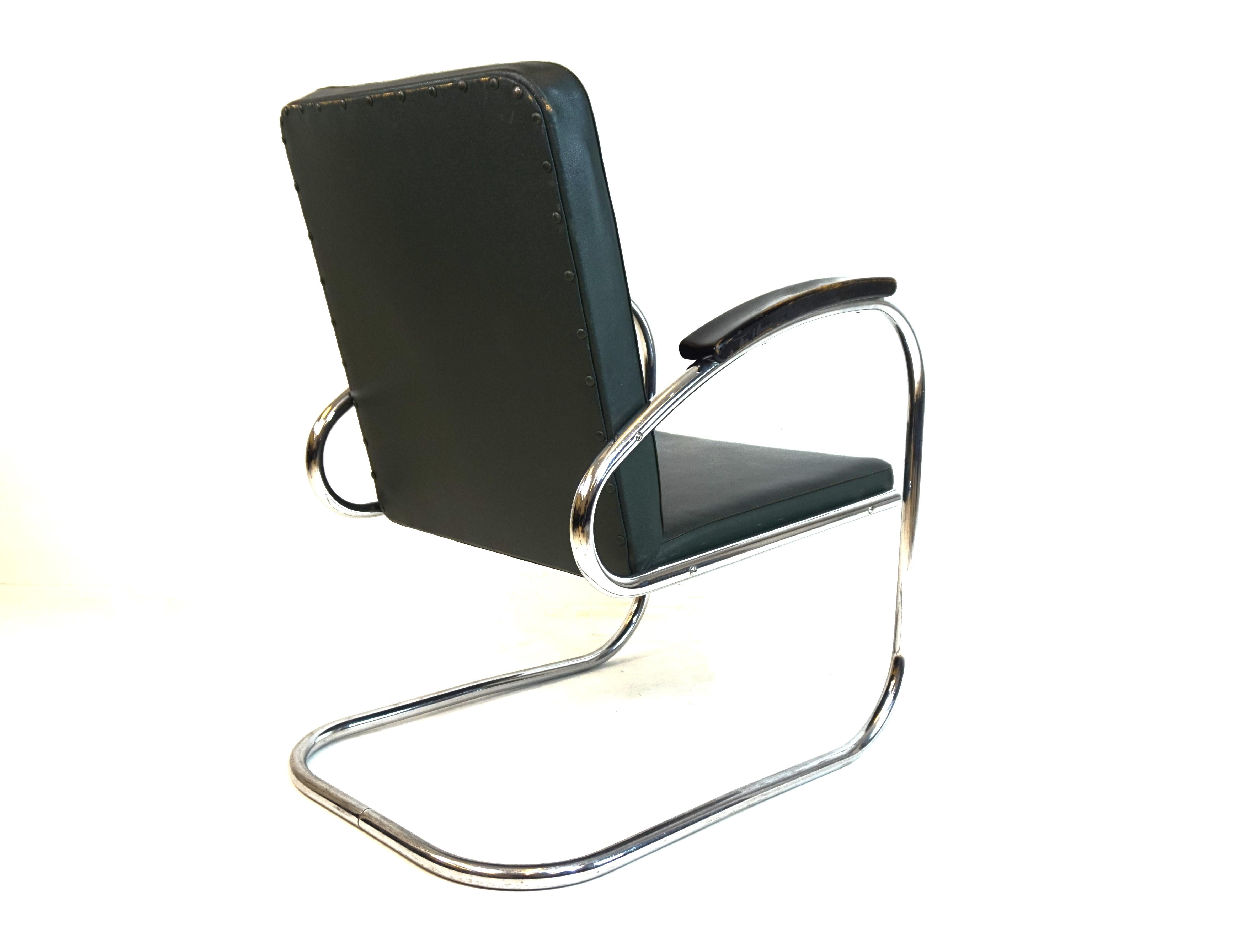 This RS7 lounge chair comes with the typical green faux leather cover of this time. The leather and the tubular steel frame are in perfect condition and only show slight signs of wear. The wooden armrests are painted black and have a very attractive