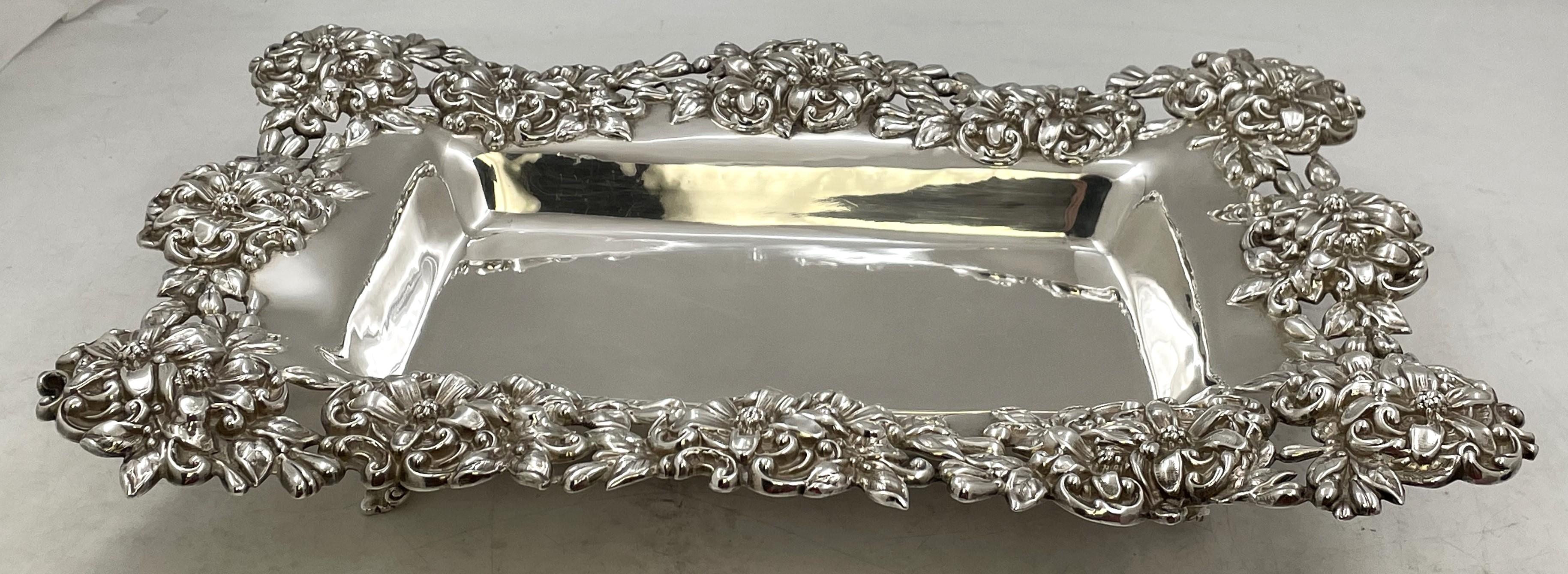 Piatto in argento sterling Mauser su 4 gambe, in stile Art Nouveau e risalente alla fine del XIX o all'inizio del XX secolo, splendidamente ornato con motivi floreali in rilievo sul bordo e sulle gambe. Misura 14 7/8'' per 10 5/8'' per 2 5/8'' di