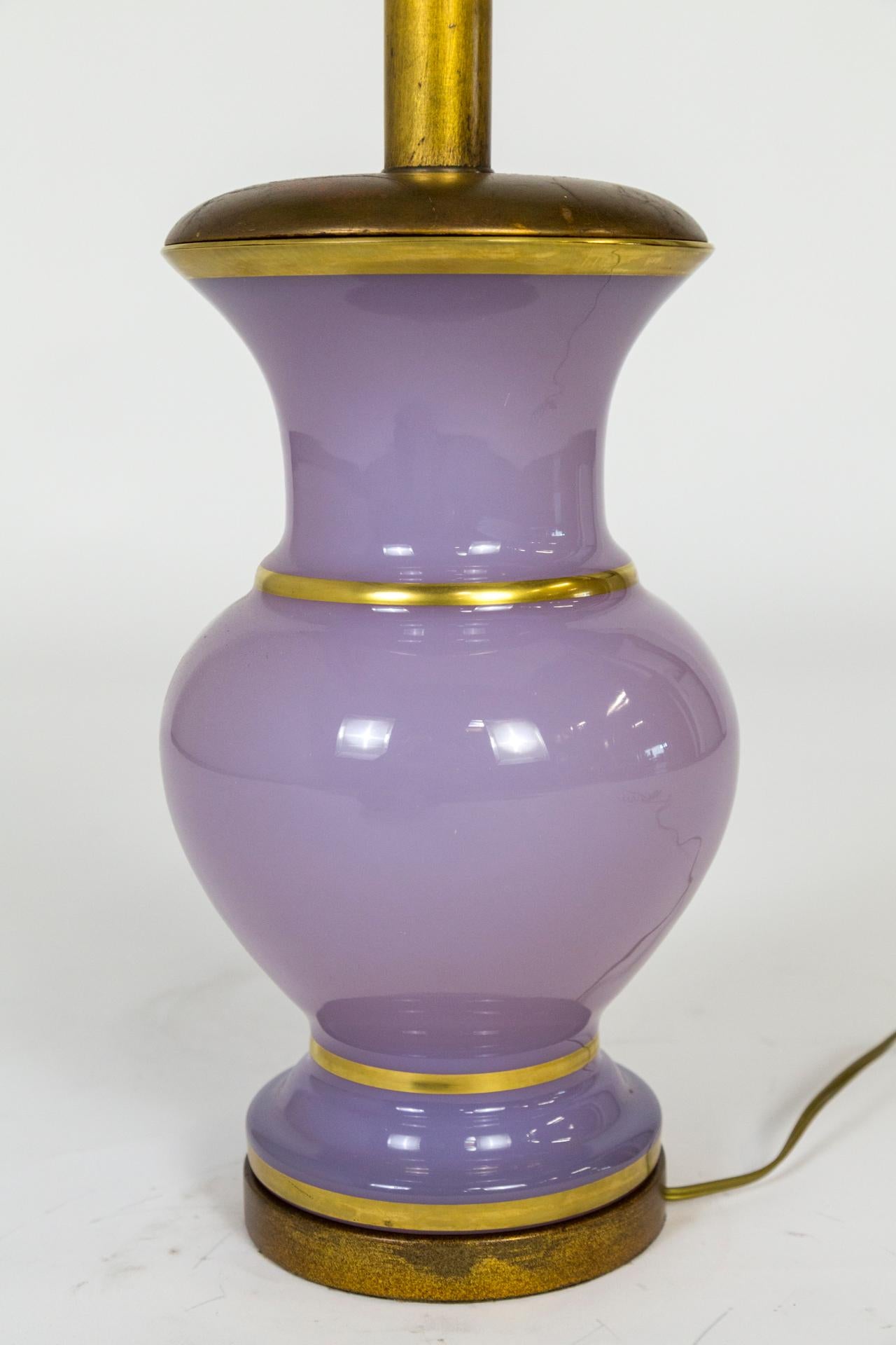 An elegant lamp of Alexandrite, also known as Neodymium, glass  in a complex color that is normally lilac-mauve (in natural and incandescent light), but turns to a pale smokey blue when under fluorescent light. In an urn shape; with a gold accent