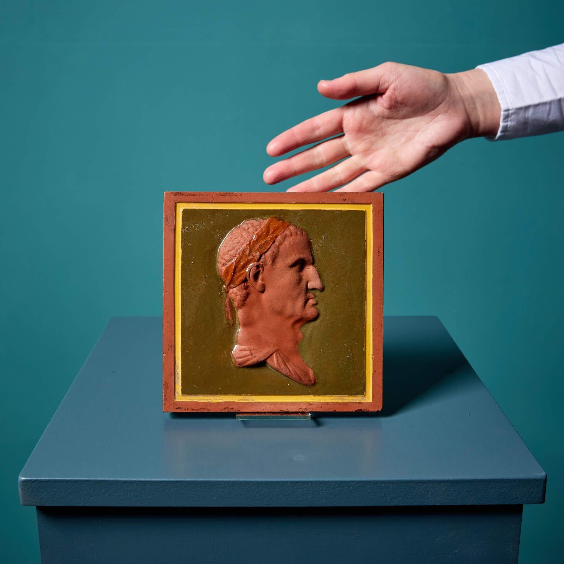 Carreau décoratif de 6 pouces en terre cuite pressée par Maw & Co. (estampillé) décoré d'un portrait de profil néoclassique en relief devant un fond vert olive et une bordure jaune.

Ex. Collectional britannique, le personnage a un air néoclassique