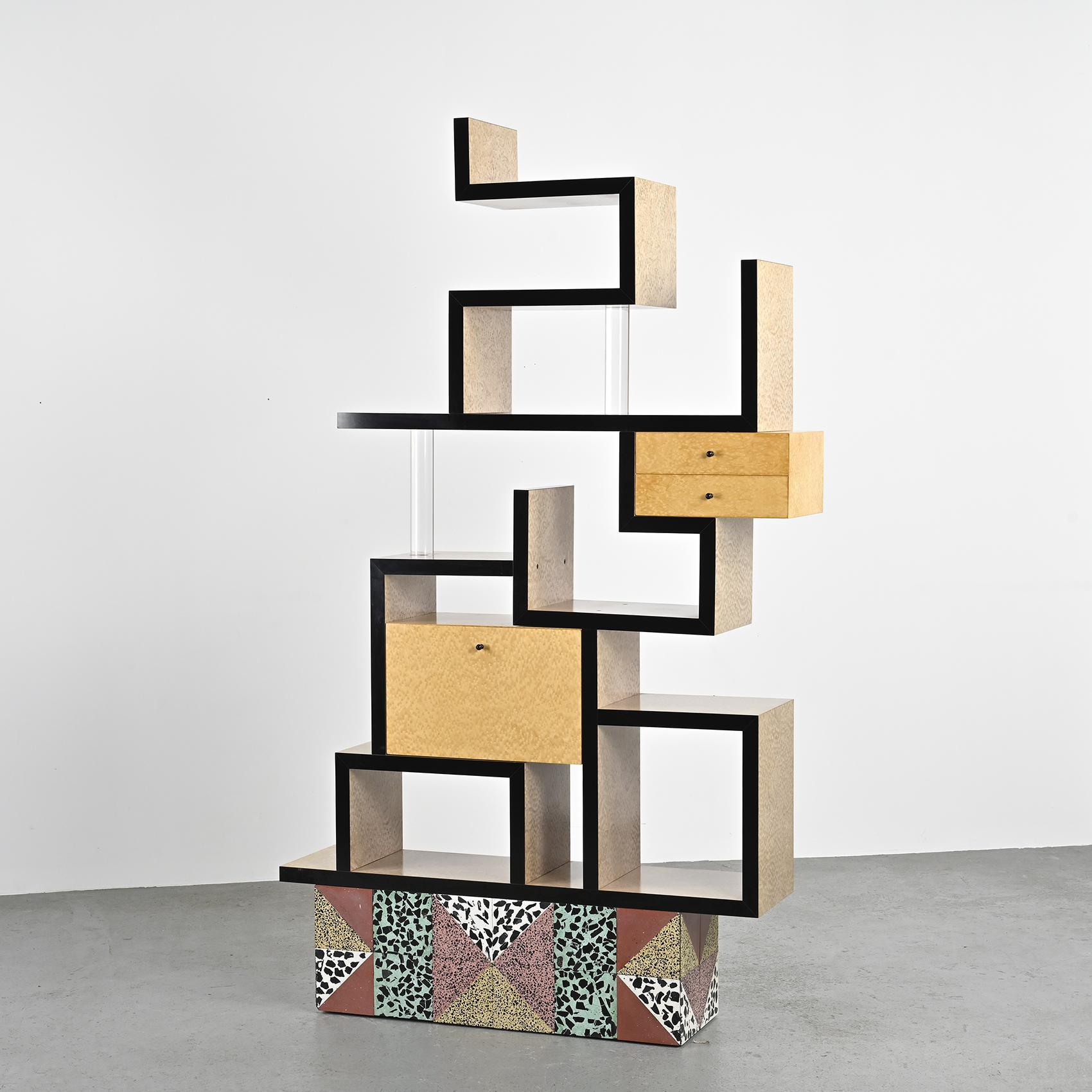 The Max bookcase by Ettore Sottsass, created by the famous Italian designer, is an iconic piece that reflects his distinct aesthetic. Designed in the 1980s, this bookcase is characterized by a bold and colorful structure, typical of the Memphis