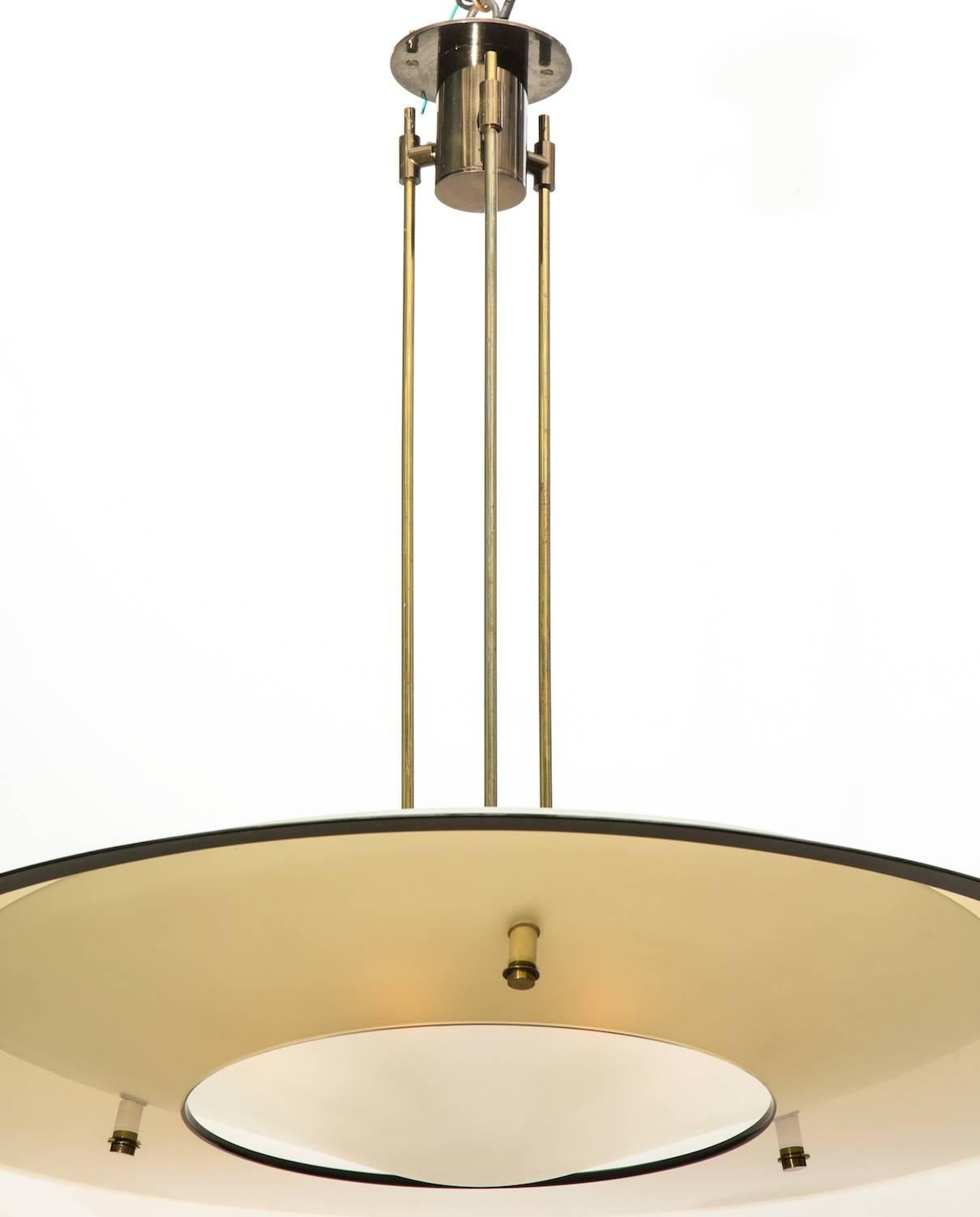 Saucer chandelier by Max Ingrand for Fontana Arte. Model #2097, consisting of a pale amber glass shade and an acid-etched white glass diffuser. Brass structure and mounts and nine standard sized sockets. All wiring and sockets have recently been