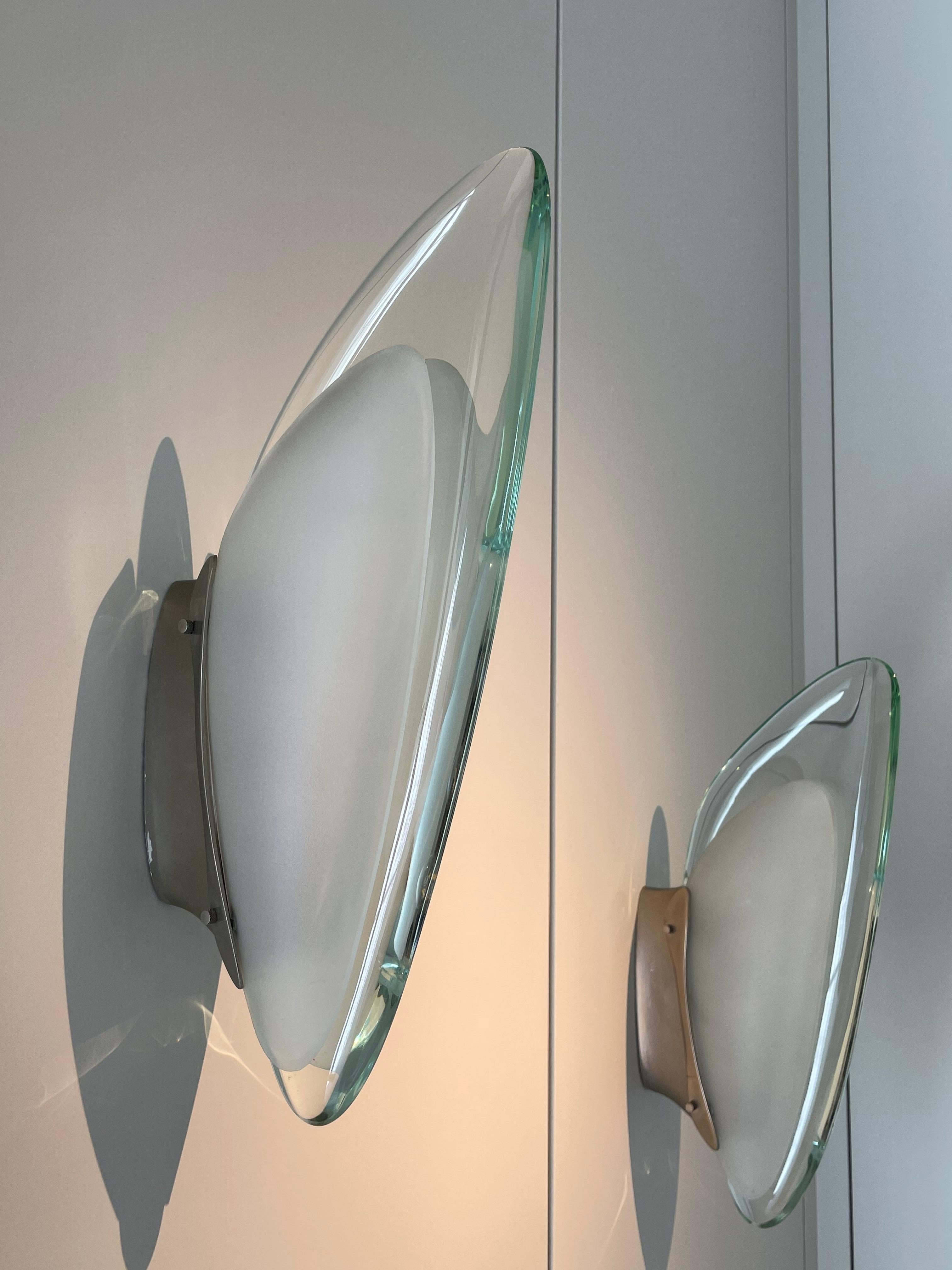 Pair of wall lamp by Max Ingrand for Fontana Arte Italy, 1965.
Shell made of a thick slightly green tinted glass and two sandblasted glass lobes, nickel-plated brass plate,
accommodating three small lights.
Excellent vintage patina.