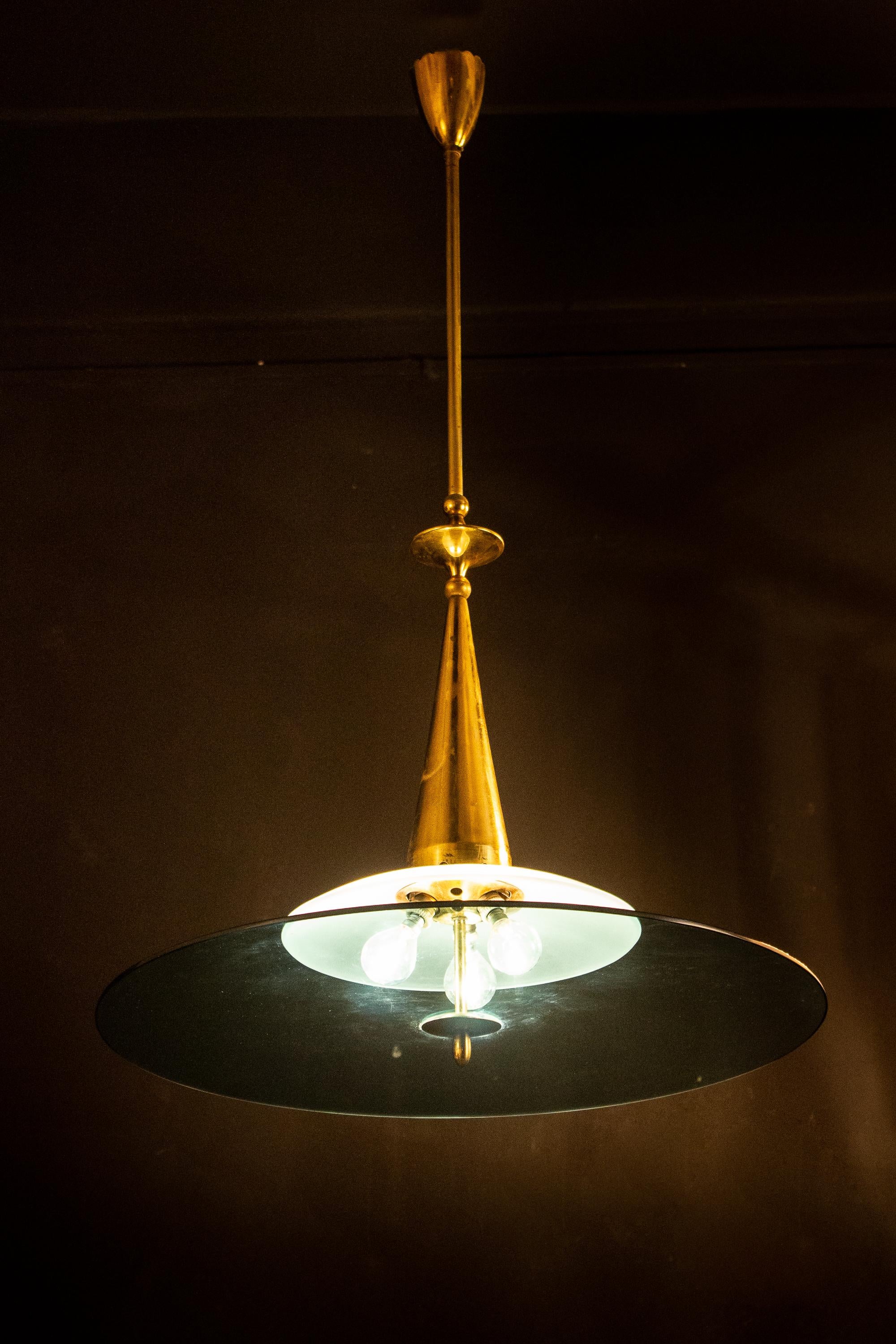 Elegant Minimalist chandelier attributed to Max Ingrand for Fontana Arte, with a frosted glass bowl and a large blue crystal shade supported by sophisticated polished brass hardware.
The glasses are in perfect condition.
Three E 14 lightbulbs. We