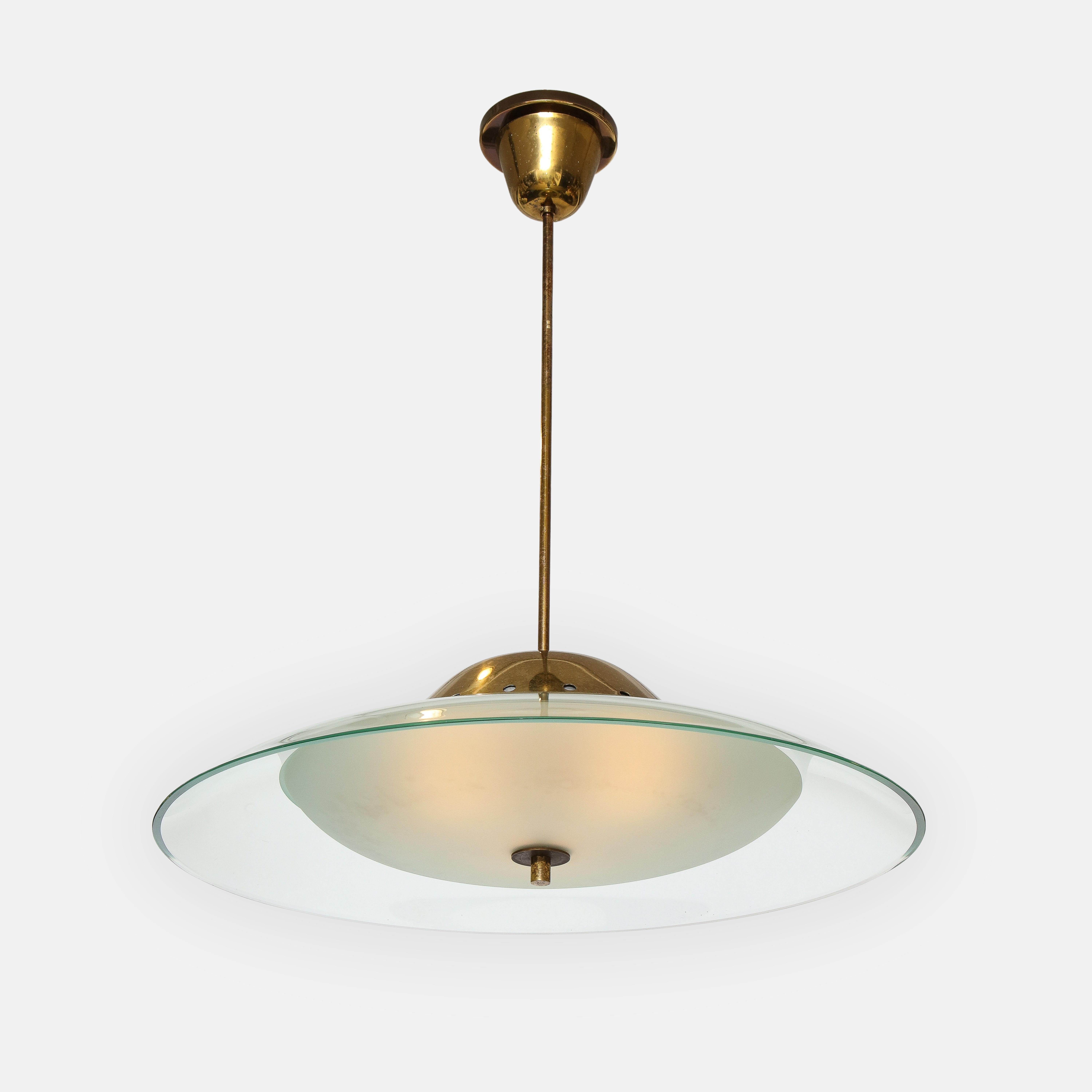 Max Ingrand per Fontana Arte modello 1239 elegante lampadario o plafoniera a sospensione con grande disco curvo in cristallo lucido in cima al diffusore in vetro smerigliato con ornamento centrale in ottone, sospeso su supporto in ottone, stelo e
