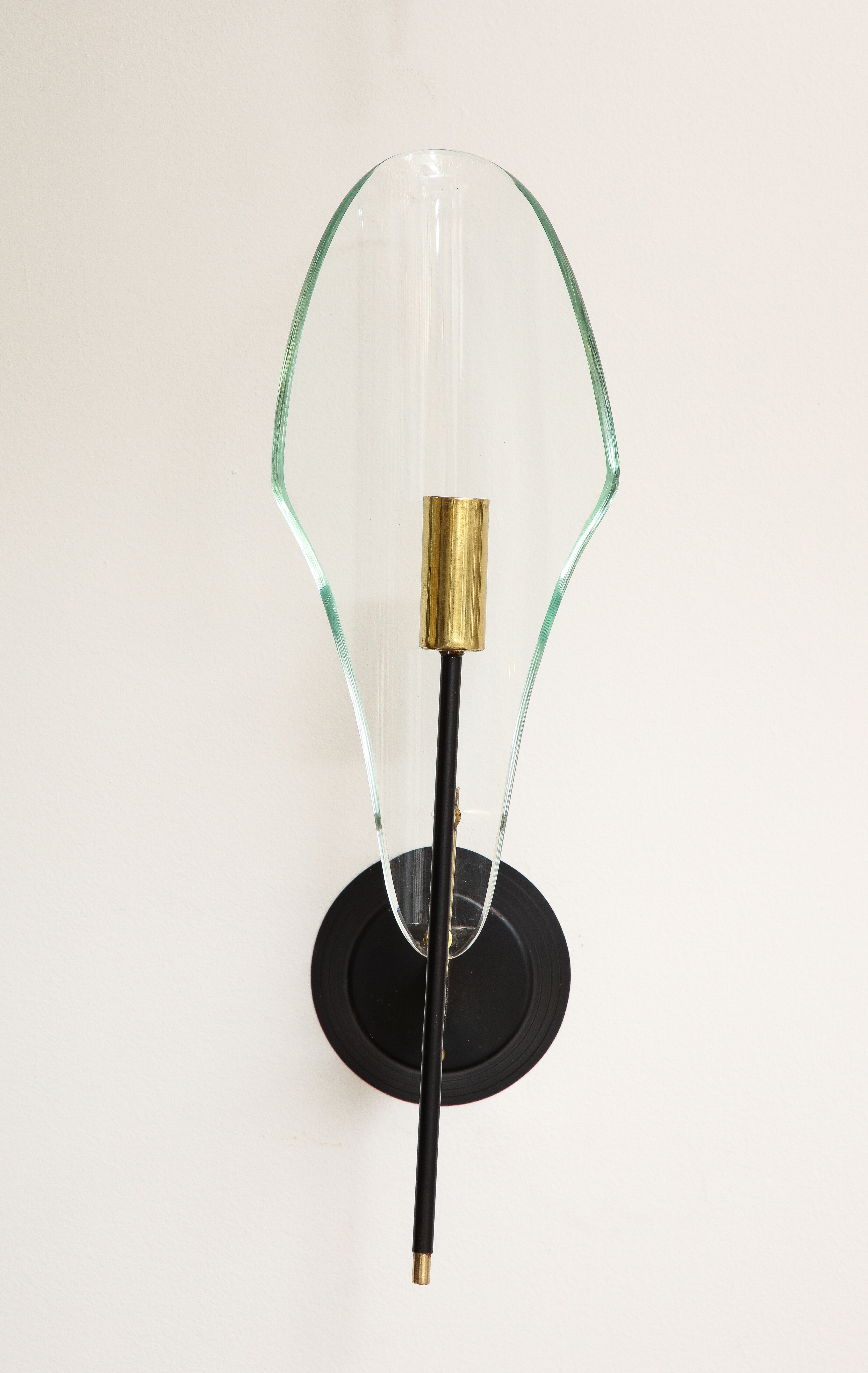 Applique da parete con vetro trasparente a forma di scudo, con un singolo candelabro in ottone, sostenuto da un supporto circolare in metallo verniciato nero. (Tre disponibili). 
di Max Ingrand per Fontana Arte, Italia, circa 1960
Dimensioni: 16