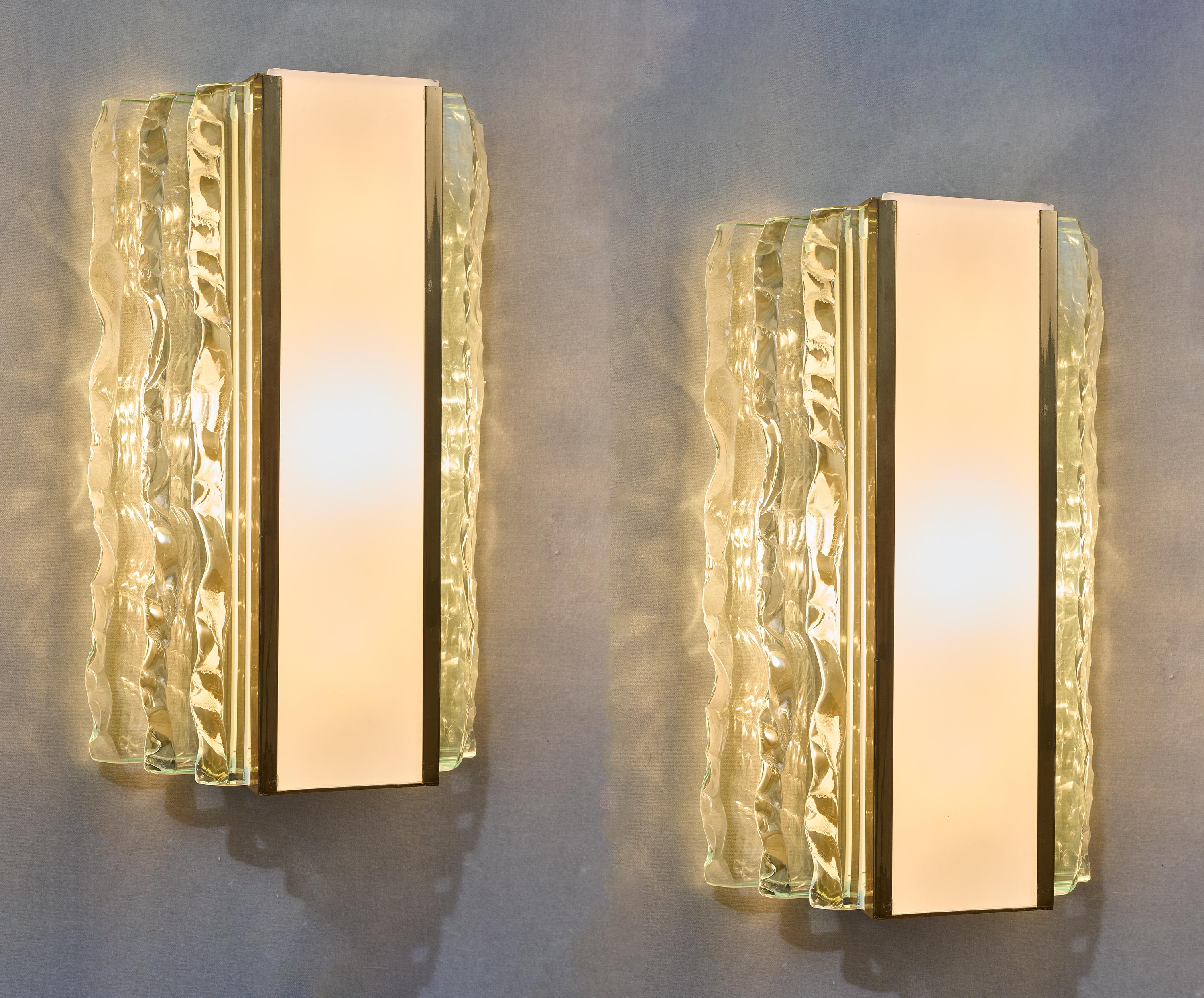 Max Ingrand (1908 - 1969) for Fontana Arte 

A striking pair of long rectangular sconces by Max Ingrand for Fontana Arte, in chiseled crystal and white glass on brass mounts. Three rows of exceptionally thick, luminous crystal slabs with wavy,