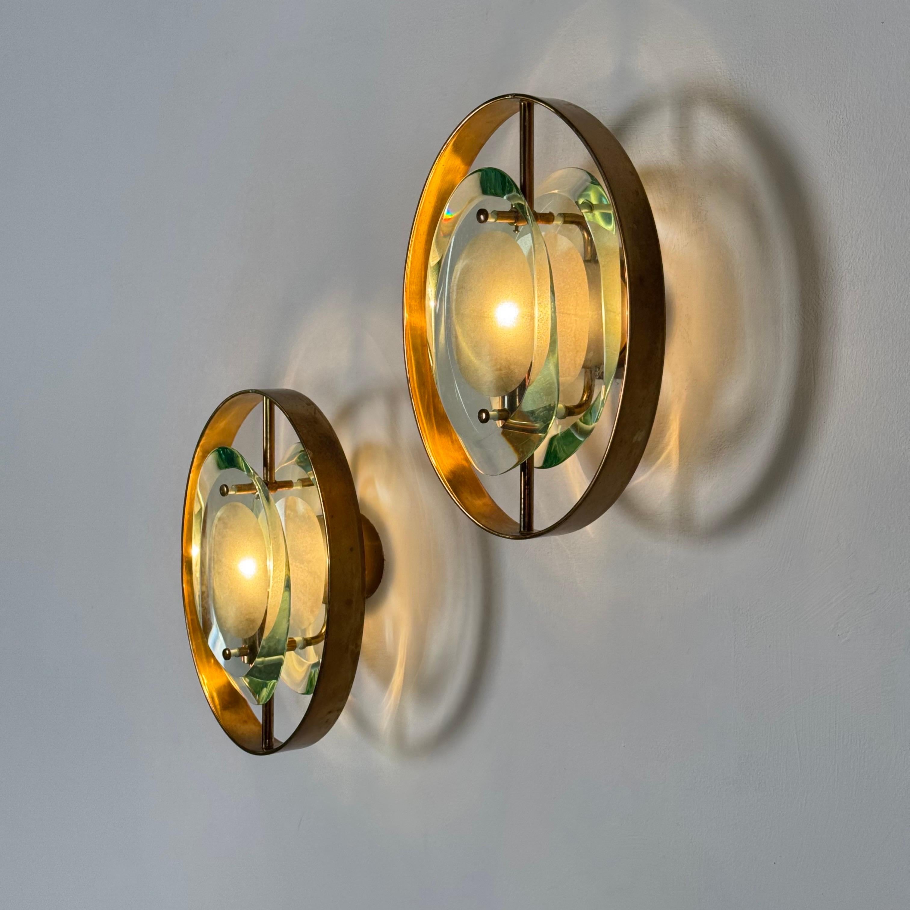 A rare and authentic pair of ‘Micro’ sconces, model 2240, designed by Max Ingrand for Fontana Arte in the 1950s.
Each sconce features double profiled glass panels: two thick, polished lenses with acid-etched centers that diffuse the light in a