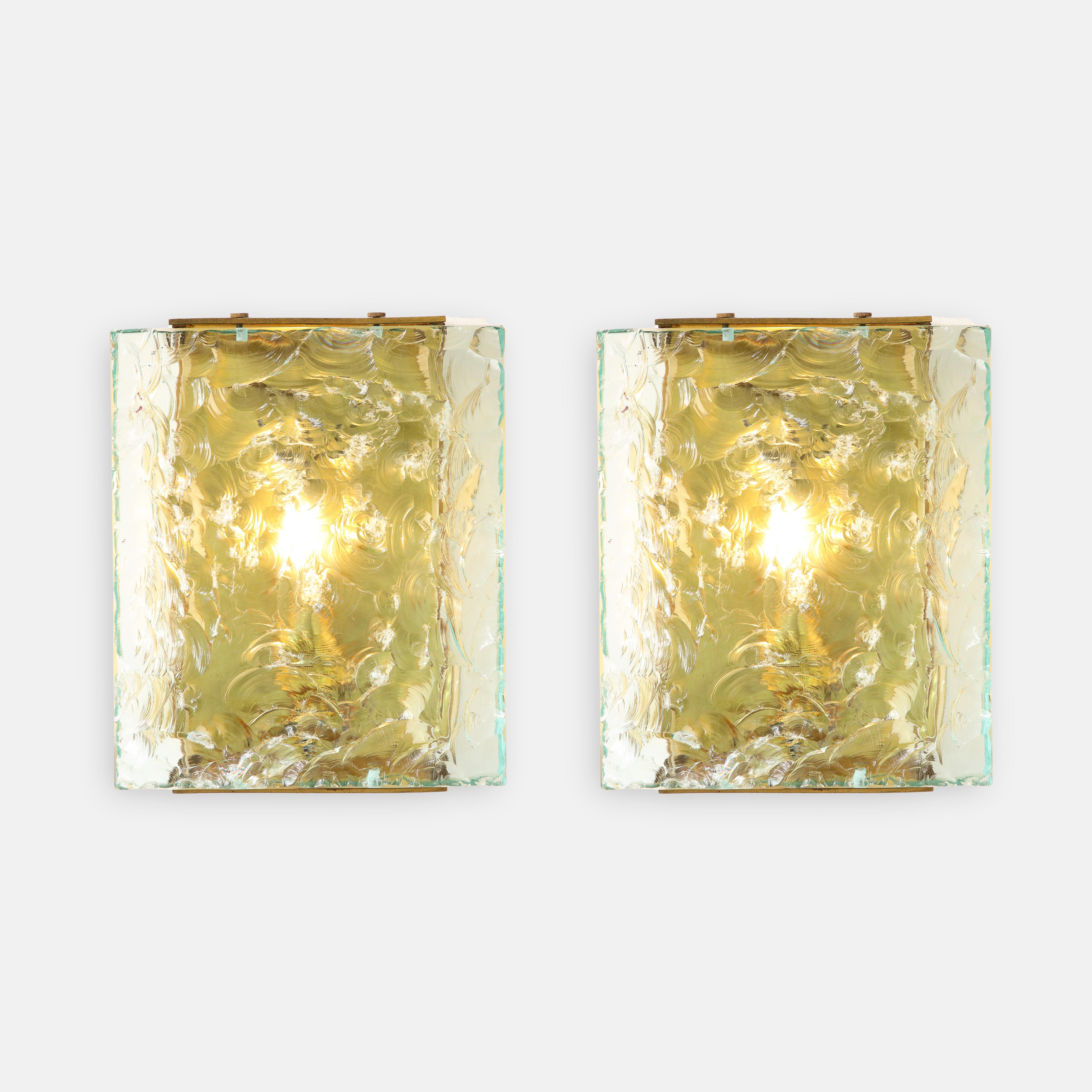 Max Ingrand for Fontana Arte exquisite pair of sconces model 2311 in thick chiseled glass with brass fittings and yellow colored glass side panels, Italy, circa 1964. These extraordinary sconces exhibit the delicate and harmonious combination of the
