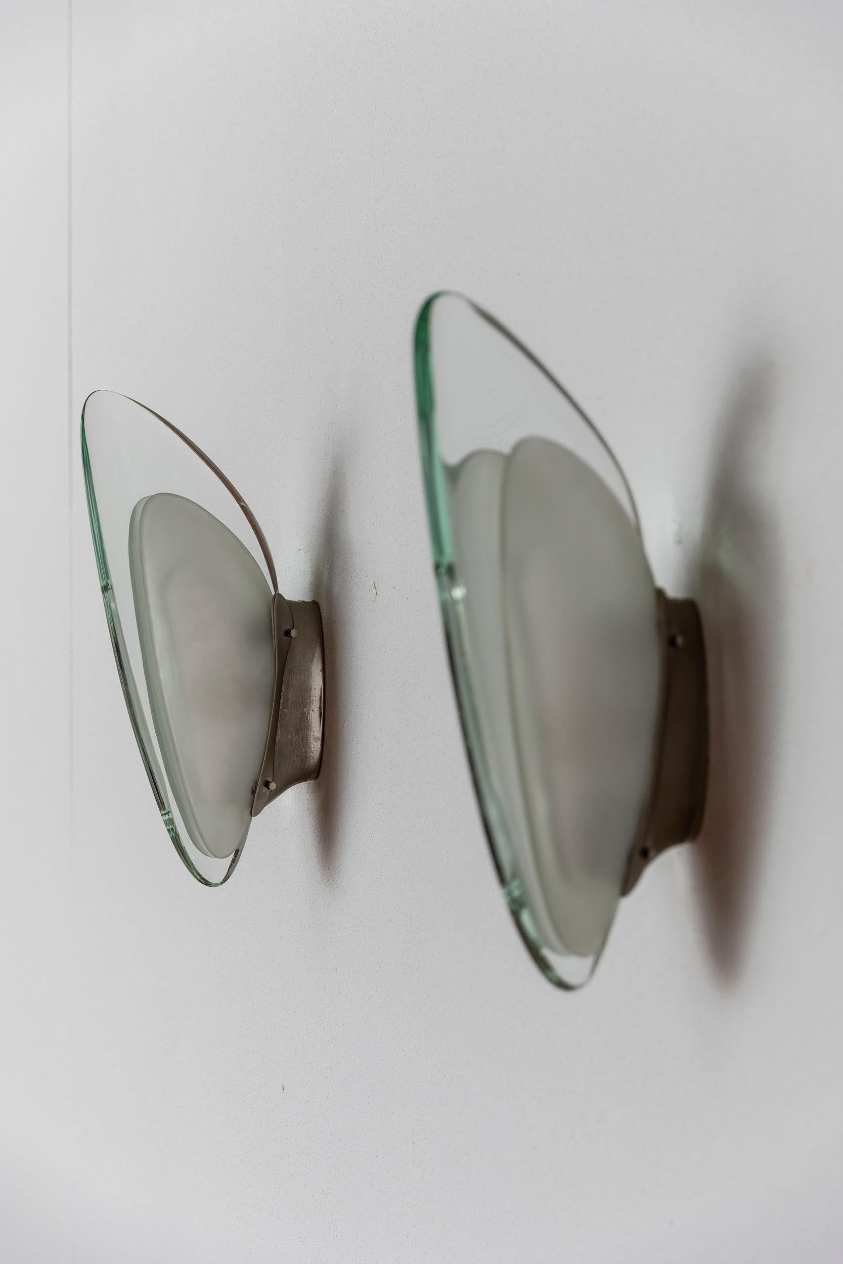 Max Ingrand für Fontana Arte Wandleuchter, Italien, 1957 ca. 
Paar Wandleuchter Modell 1552, entworfen von Max Ingrand für Fontana Arte. Organisch geformte, zentrale Glaselemente. Gewölbte Seitenwände aus Milchglas mit vernickelten hinteren