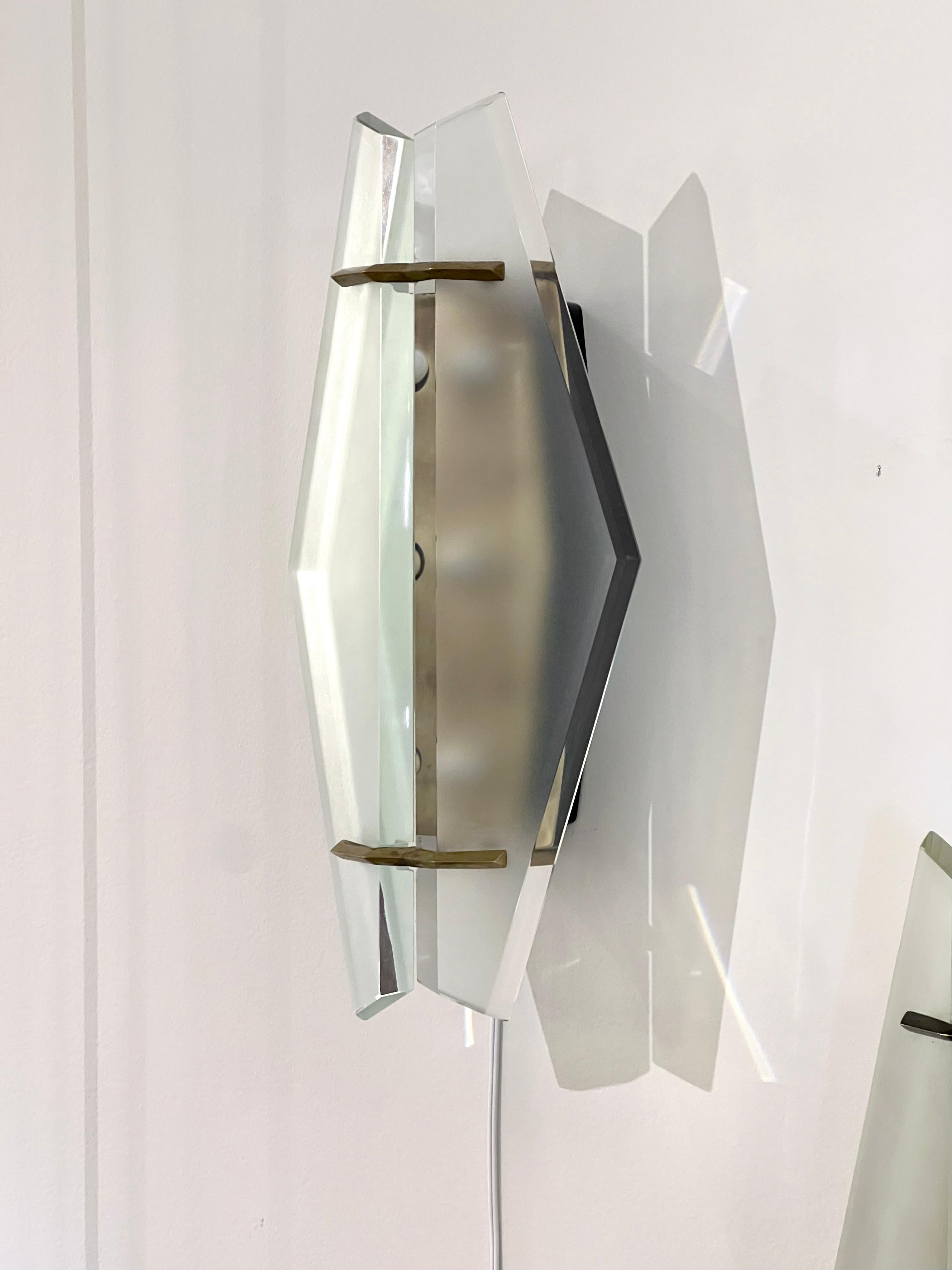 Pair of modernist sconces by Max Ingrand for Fontana Arte, with thick diamond shaped glass plates, beveled edge, held by brass mounts.