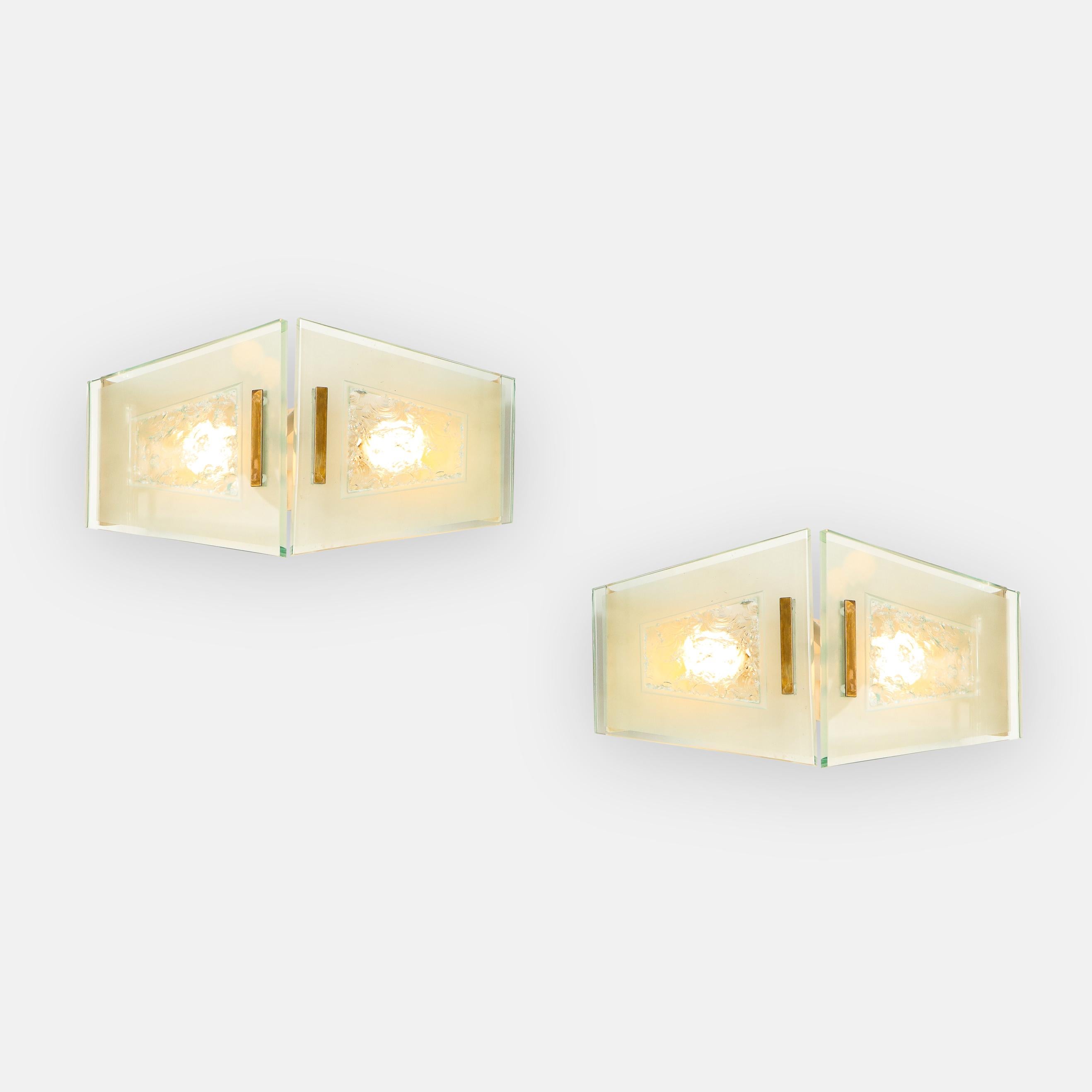 Max Ingrand for Fontana Arte rare pairs or set of 4 sconces model 2373 consisting each of two plates of chiseled, opaque, and polished glass with polished brass mounts on painted aluminum backplates. 
Newly rewired to U.S. standards including UL