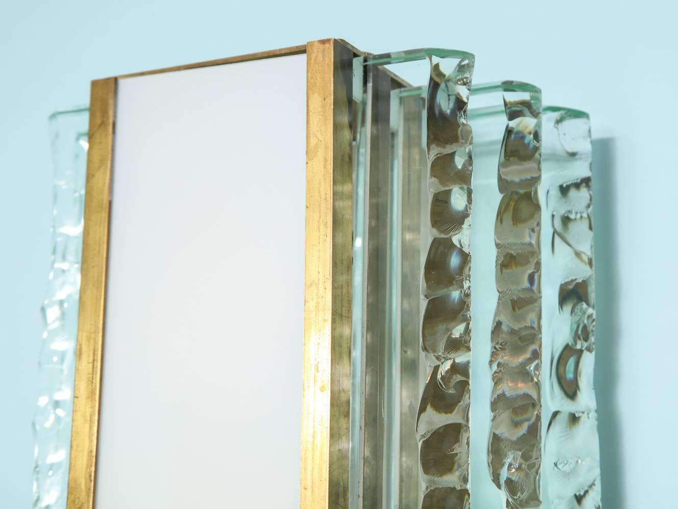 Paire d'appliques #2439 par Max Ingrand pour Fontana Arte.
Des plaques épaisses de cristal avec des bords ciselés. Façades en verre blanc et structures en laiton. Chaque applique dispose de trois douilles de type candélabre.