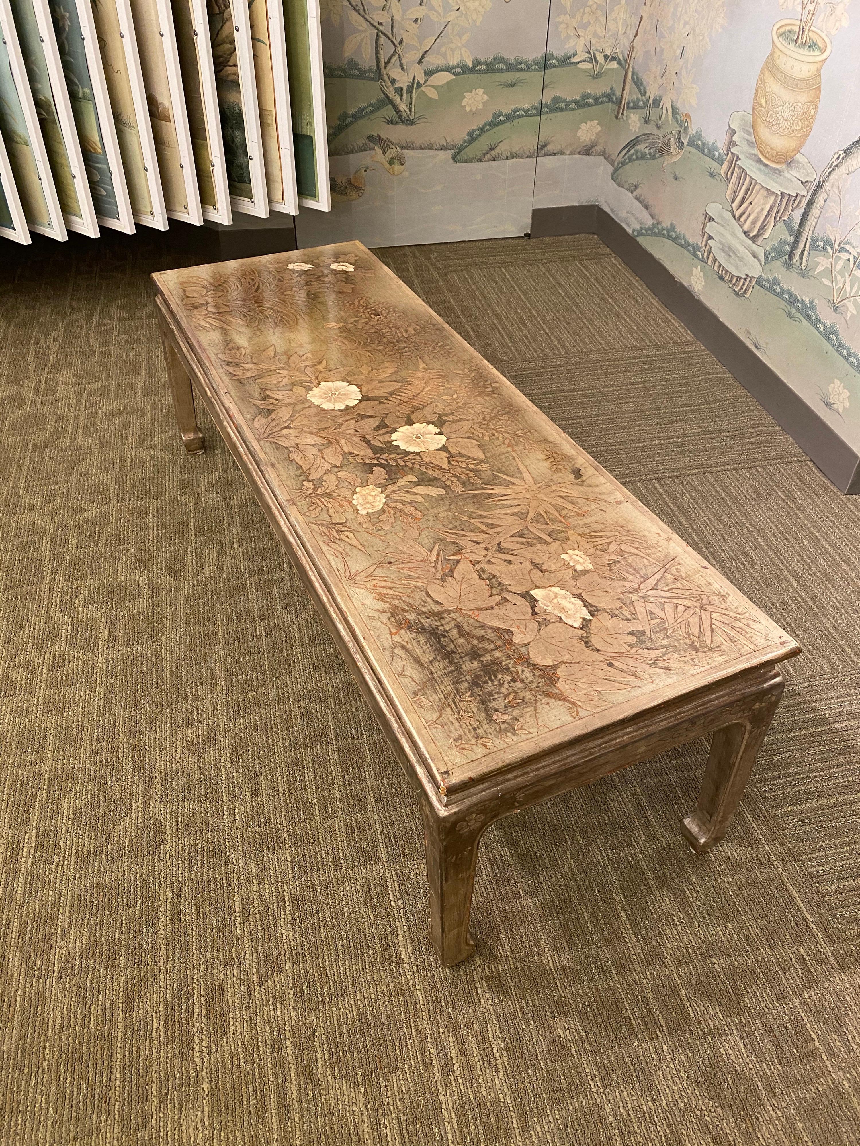 A beautiful vintage Max Kuehne coffee table, finished in silver leaf and with incised design of flowers, grasses and ferns.

The apron is also incised with vines and flowers.

This table was made in the early 1960s.