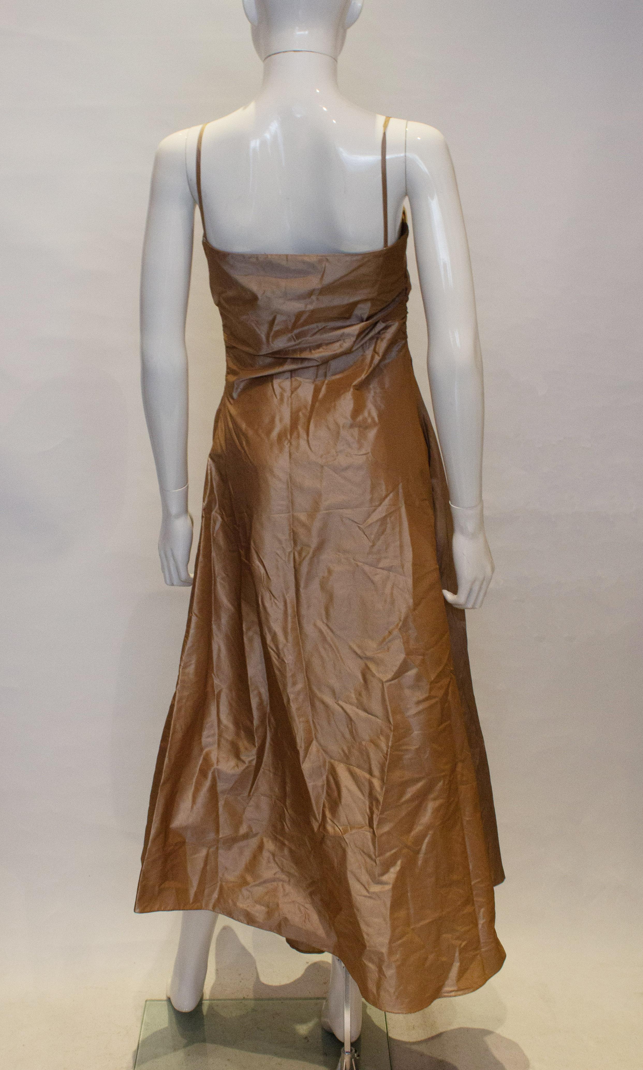 A fun  silk party dress by Max Mara. The dress is a silk tafetta fabric in a soft gold colour.
It has a side zip opening, gatering on both sides with frill and flower detail on the front.  It is unlined and has two spagetti straps.