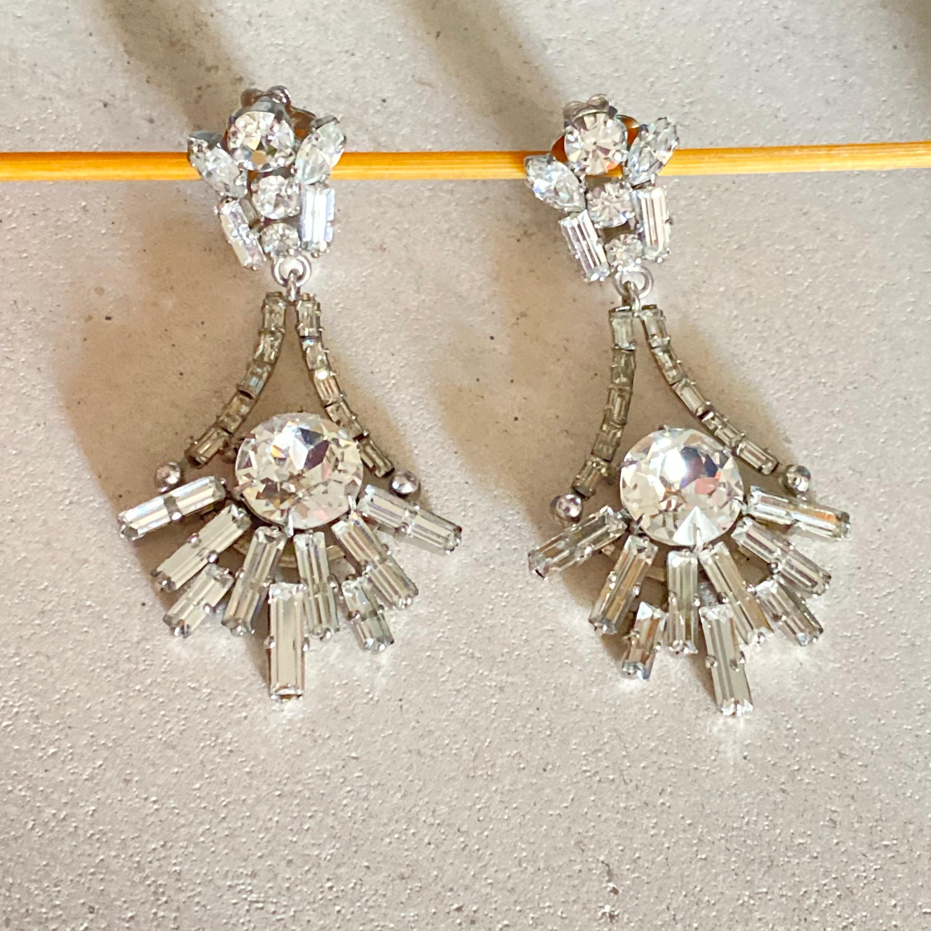 Un elegante paio di orecchini a clip dello stilista di Kaufbeuren, Max Muller, forse per Christian Dior.

Risalenti agli anni '50, questi bellissimi orecchini sono incastonati con strass trasparenti a navetta, rotondi e a baguette, con un grande