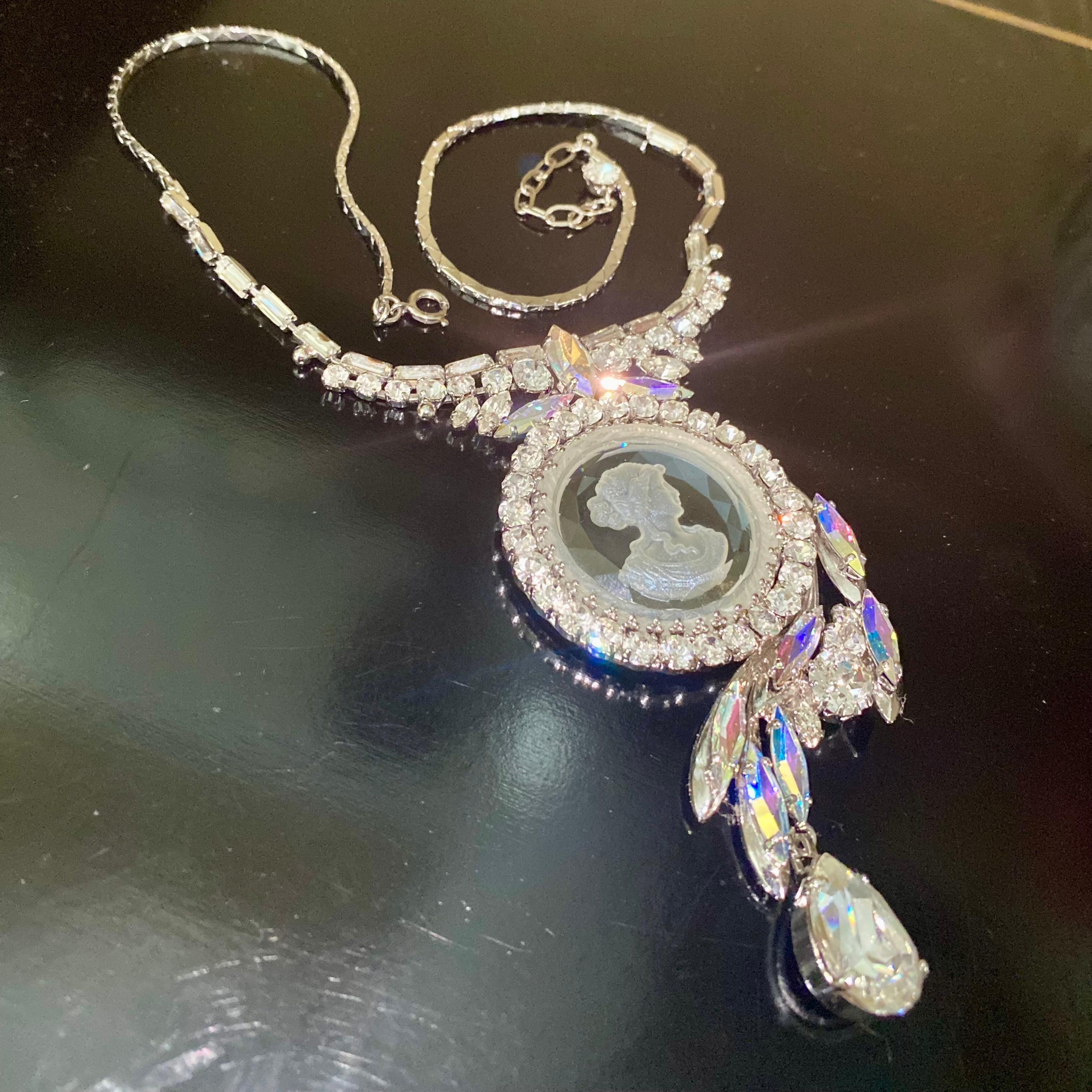 This stunning 1960’s Max Muller necklace is set with a large centre piece drop pendant with a reverse carved, clear glass Intaglio depicting a classical lady.

Surrounding the intaglio are a mix of clear and aurora borealis rhinestones. The