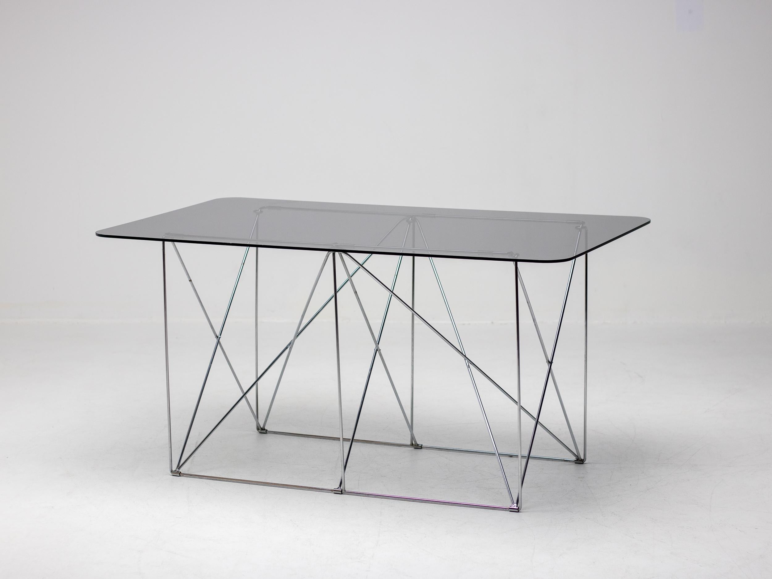 Dieser elegante klappbare Tisch aus verchromtem Stahl mit einer schwebenden Platte aus Rauchglas wurde von Max Sauze um 1970 in Frankreich entworfen. 

Max Sauze ist ein renommierter französischer Designer und Künstler, der für seine Pionierarbeit