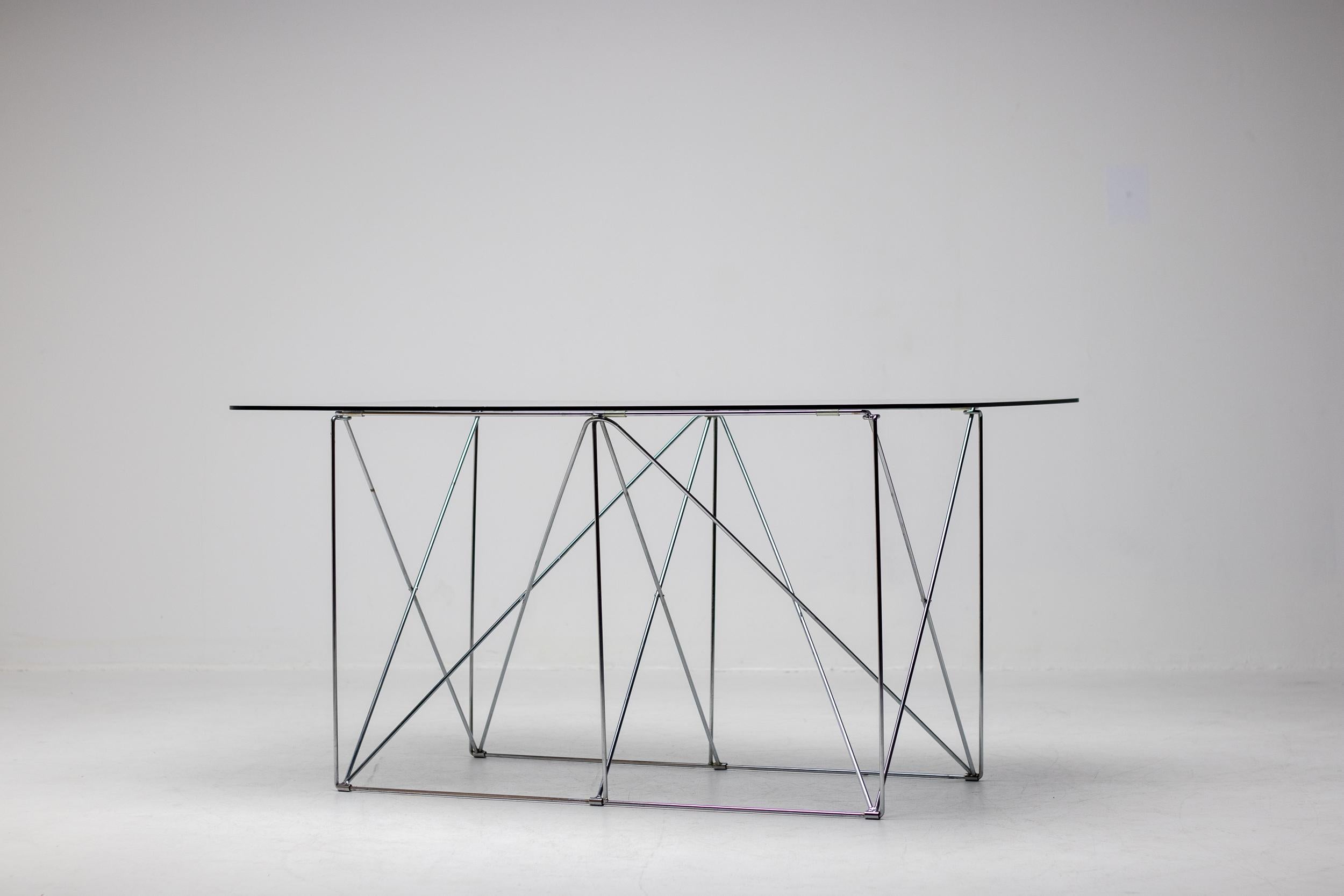Cette élégante table pliante en acier chromé avec un plateau flottant en verre fumé a été conçue par Max Steele, vers 1970, France. 

Max Sauze est un designer et artiste français de renom, célèbre pour son travail de pionnier dans le domaine du