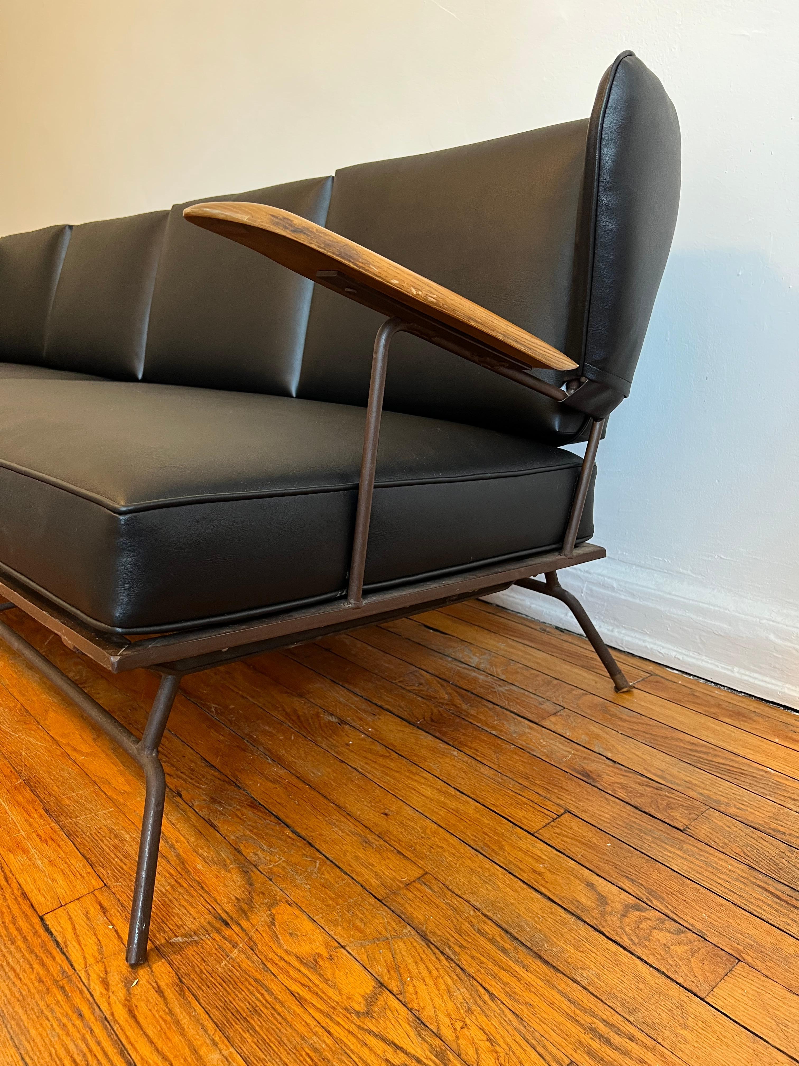 Sehr seltenes Sofa des Schmieds, Möbeldesigners und -herstellers Max Stout aus North Carolina.

Wingback-Sofa mit Armlehnen aus Holz, patiniertem Metall und schwarzem Naugahyde-Bezug. Unsere Galerie hat das Glück, das gleiche Sofa in Orange (auf der