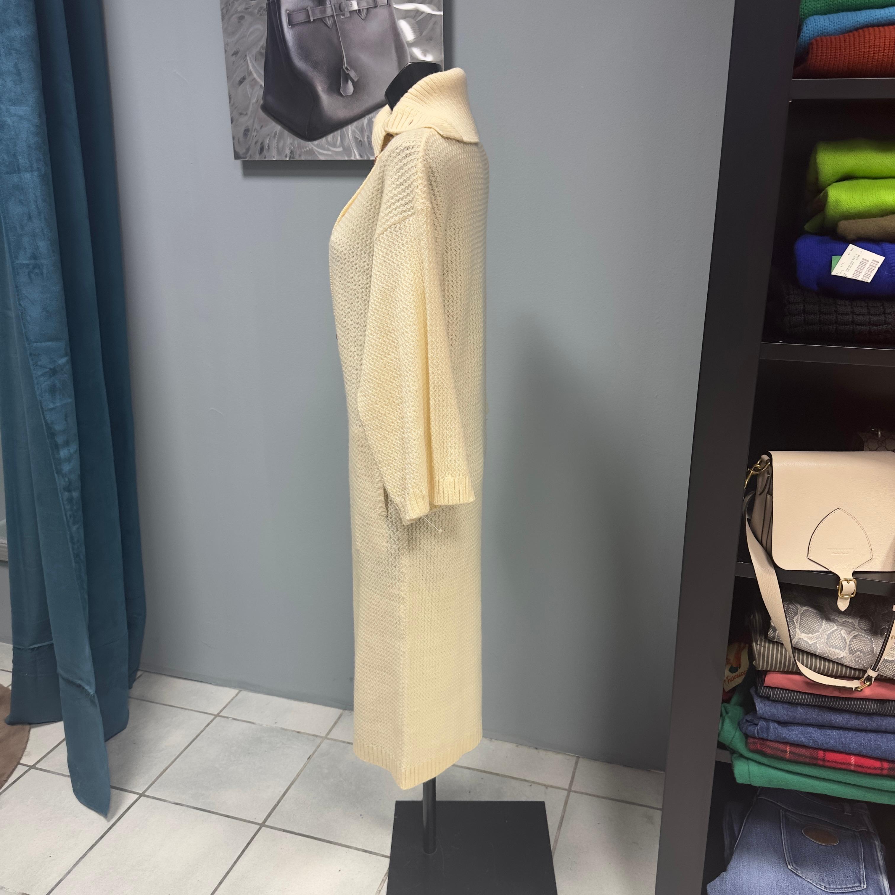 Cremefarbenes Maxikleid von Caumont mit lederbezogenen Knöpfen. Das Kleid ist aus den 1980er Jahren, noch gekrempelt, mit einem breiten hohen Kragen und Seitentaschen 
Caumont war der erste Designer von Balmain, und seine Kleider sind begehrt und