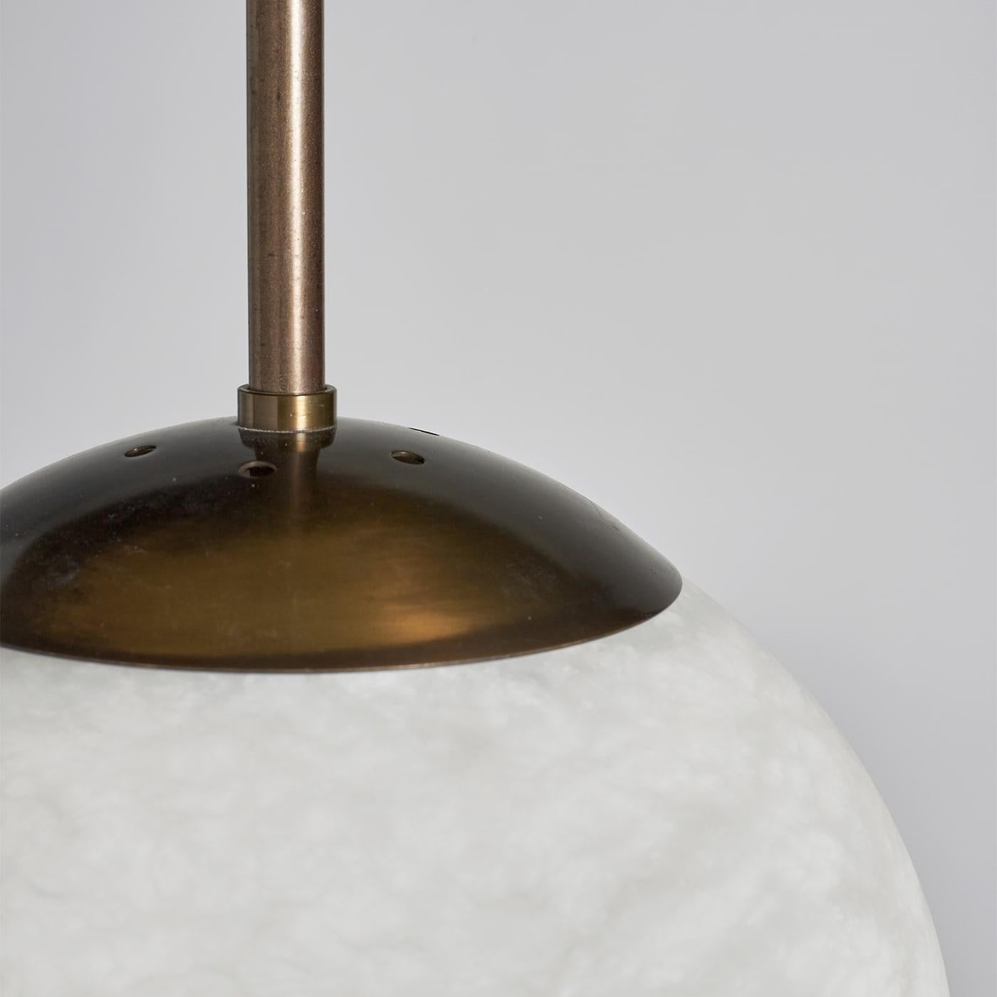 Harmonious geometric volumes surprisingly reveal in this pendant lamp a poetic inspiration evoking the magic of full-moon nights. Fitted to an elegant and streamlined bronzed metal structure, the lampshade consists of a precious alabaster globe