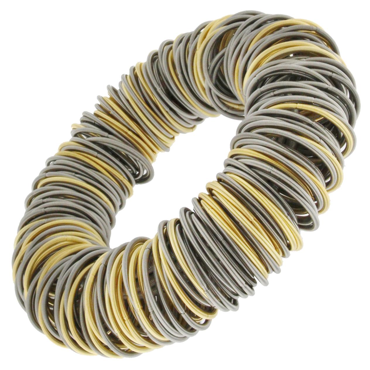 Balanced between the exotic and the industrial, the Maxi One stainless steel and gold plated bracelet is strikingly elegant. The hardness of steel is softened by a clever structure of elastic hoops of finely spun springs, some plated with gold. By