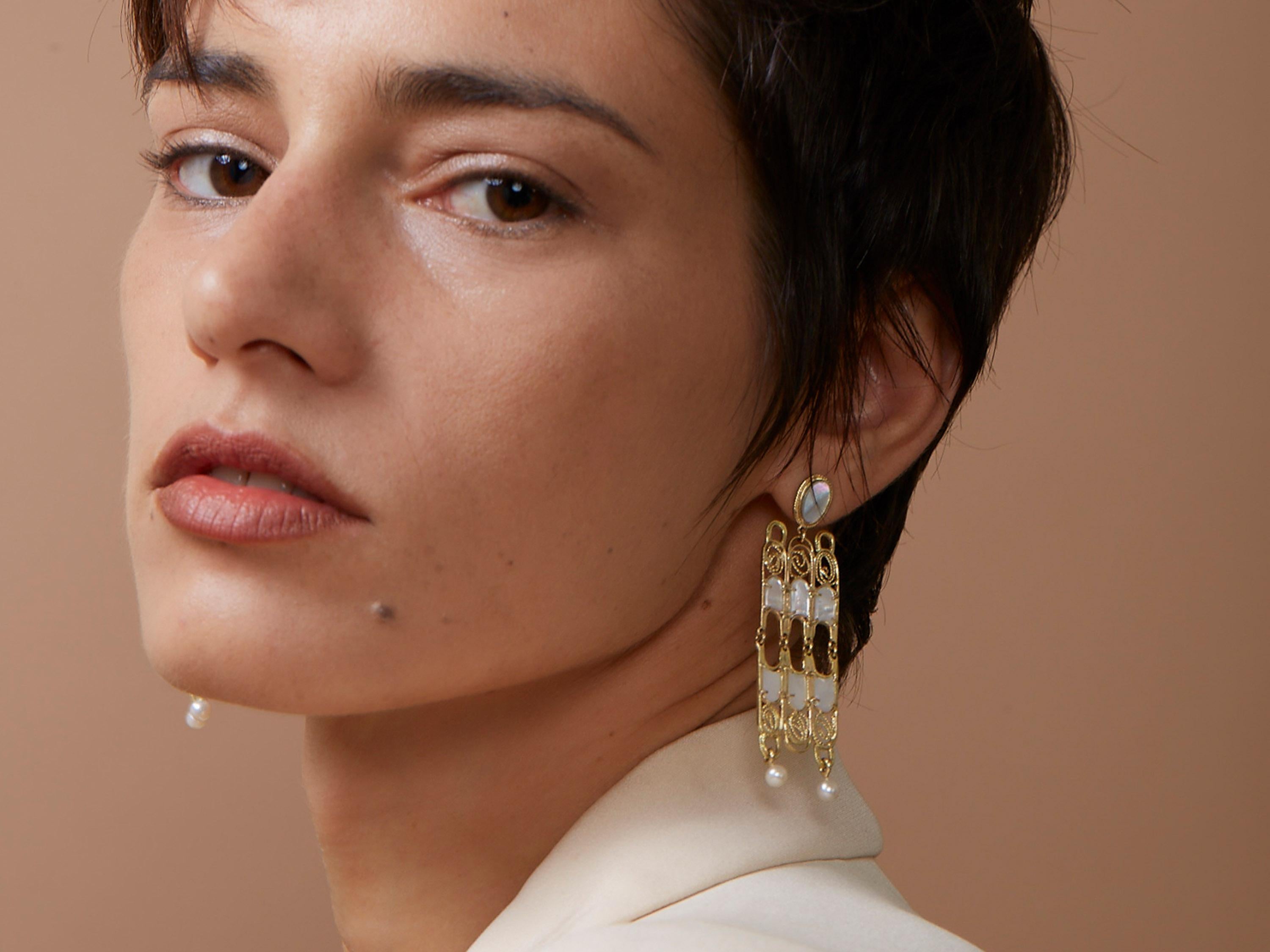Make an elegant and bold statement in these large chandelier style earrings. Crafted in the ancient filigree method where gold wires are arranged into patterns and fused together to create lightweight frames. These earrings feature hand cut mother