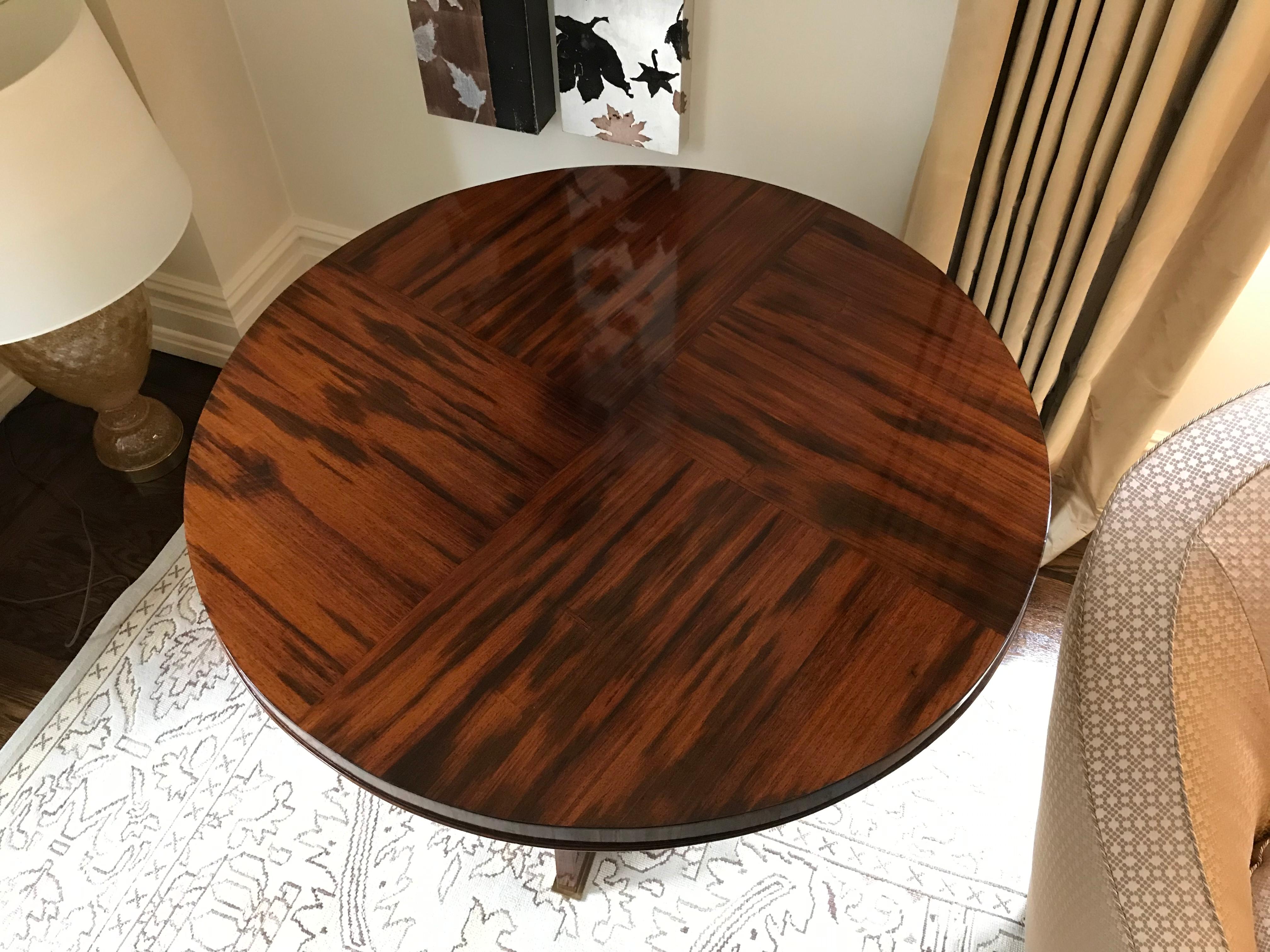 Round, quarter veneered rosewood table with a molding on the lower lip. Table is supported on a base composed of interesting tapered trestles with arched bottoms on bronze pads. Originally purchased from Bernd Goeckler with receipt.