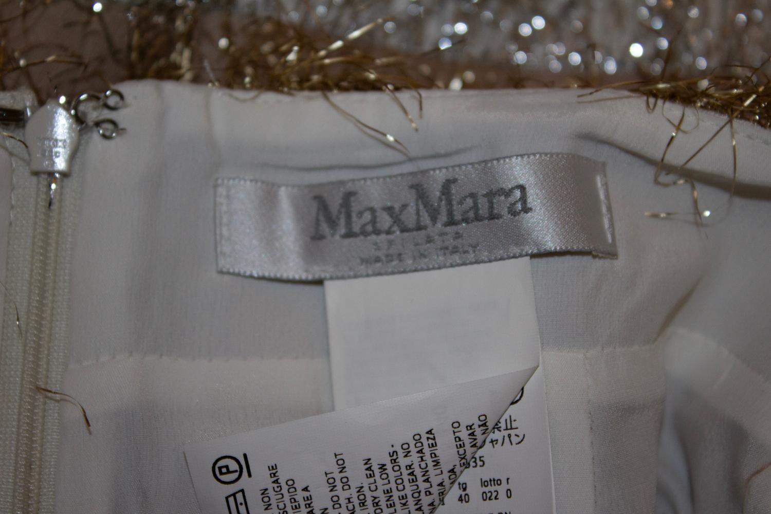 Una falda divertida de la línea principal de MaxMara. La falda tiene un forro de mezcla de seda y está decorada en la parte exterior con bandas horizontales de tejido similar al oropel en tonos dorado, plateado y bronce pálido.
Tiene una cremallera