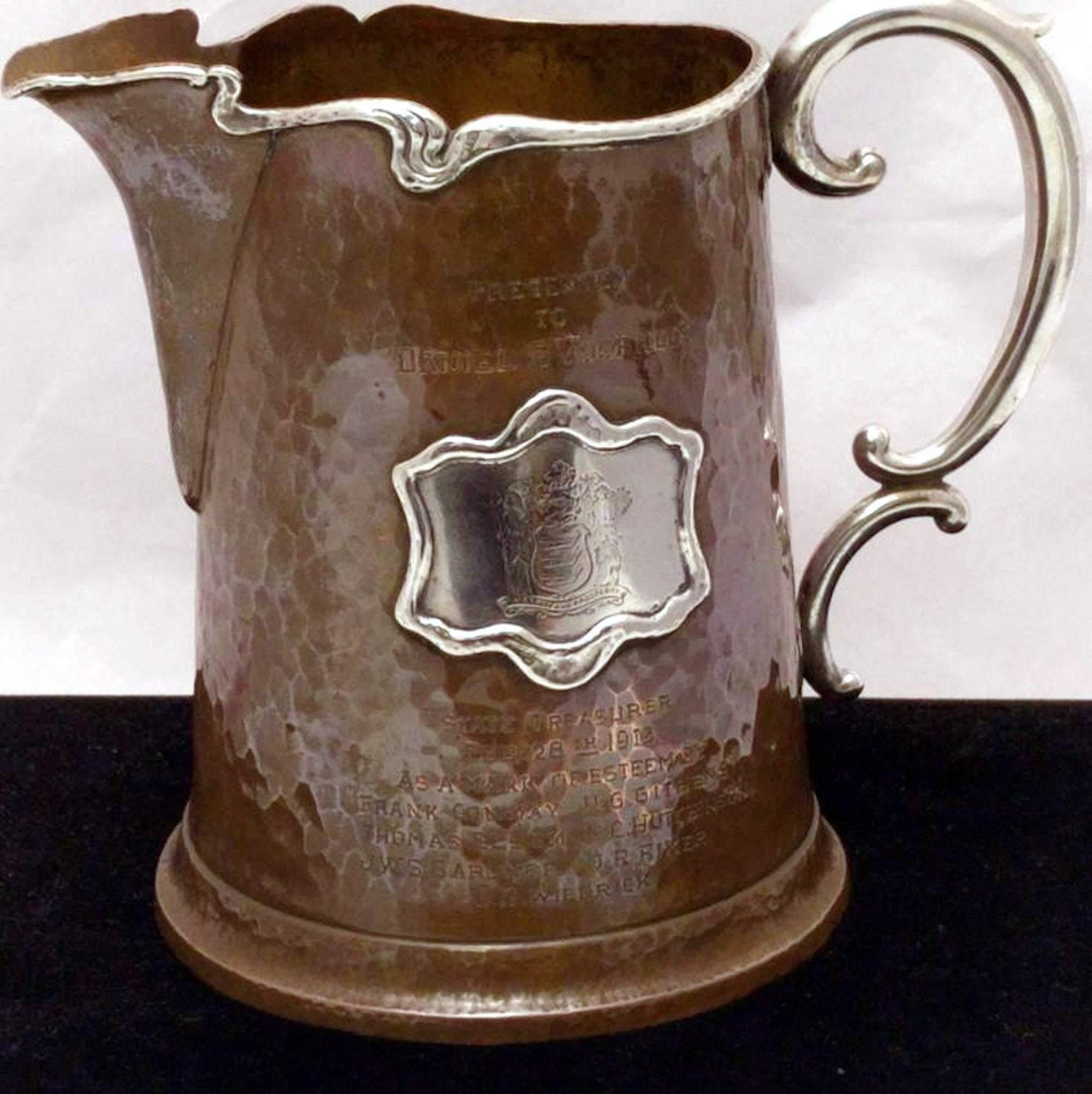 Beer pitcher by Maxwell & Berlet, Philadelphia-based makers of jewelry and silver in the early 20th century, in Aesthetic Movement, made of applied silver on copper. Measuring 6.5 inches tall and 8 inches from handle to spout.

Engraved on