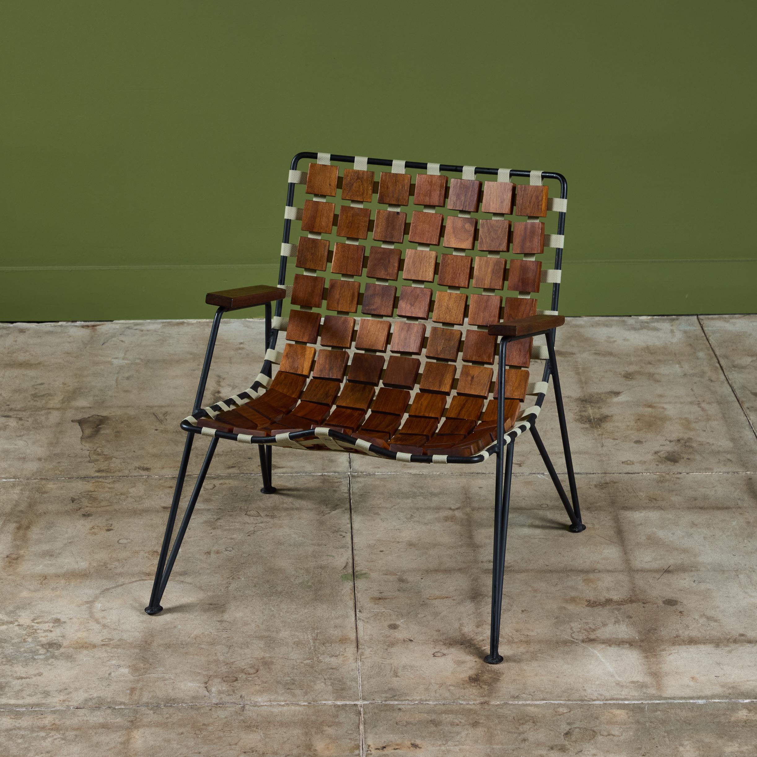 Sillón diseñado por Maxwell Yellen en 1954. El ligero armazón de alambre tiene correas a lo largo del asiento y el respaldo, con bloques cuadrados de nogal en todo el contorno de la silla que se amoldan a tu cuerpo. Cada brazo tiene un reposabrazos