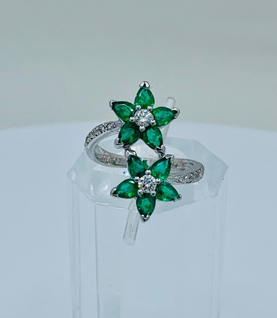 Very feminine custom made estate wrap-around ring features prong set, pear cut emerald petals which form a pair of flowers accented with round brilliant white diamond centers. Diamond pave stems run half way down the shank of the ring on both