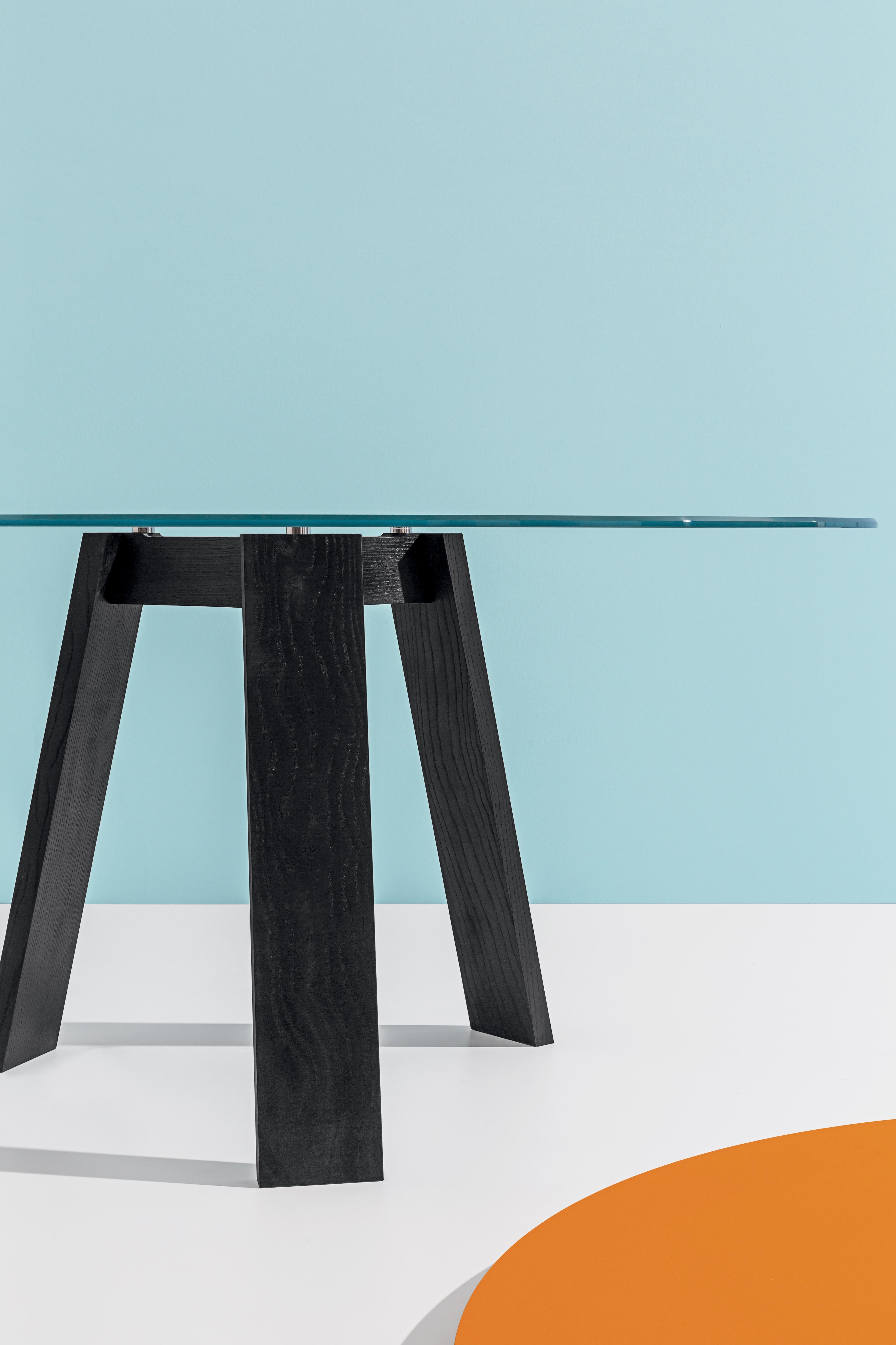 Dining table with natural ash legs with Ø59 inches tempered smoked liquid glass top.

Lars Beller’s Maya table’s nod to ancient times goes far beyond its monumental, Mayan-reminiscent aesthetic. Joining together two of earth’s most elementary