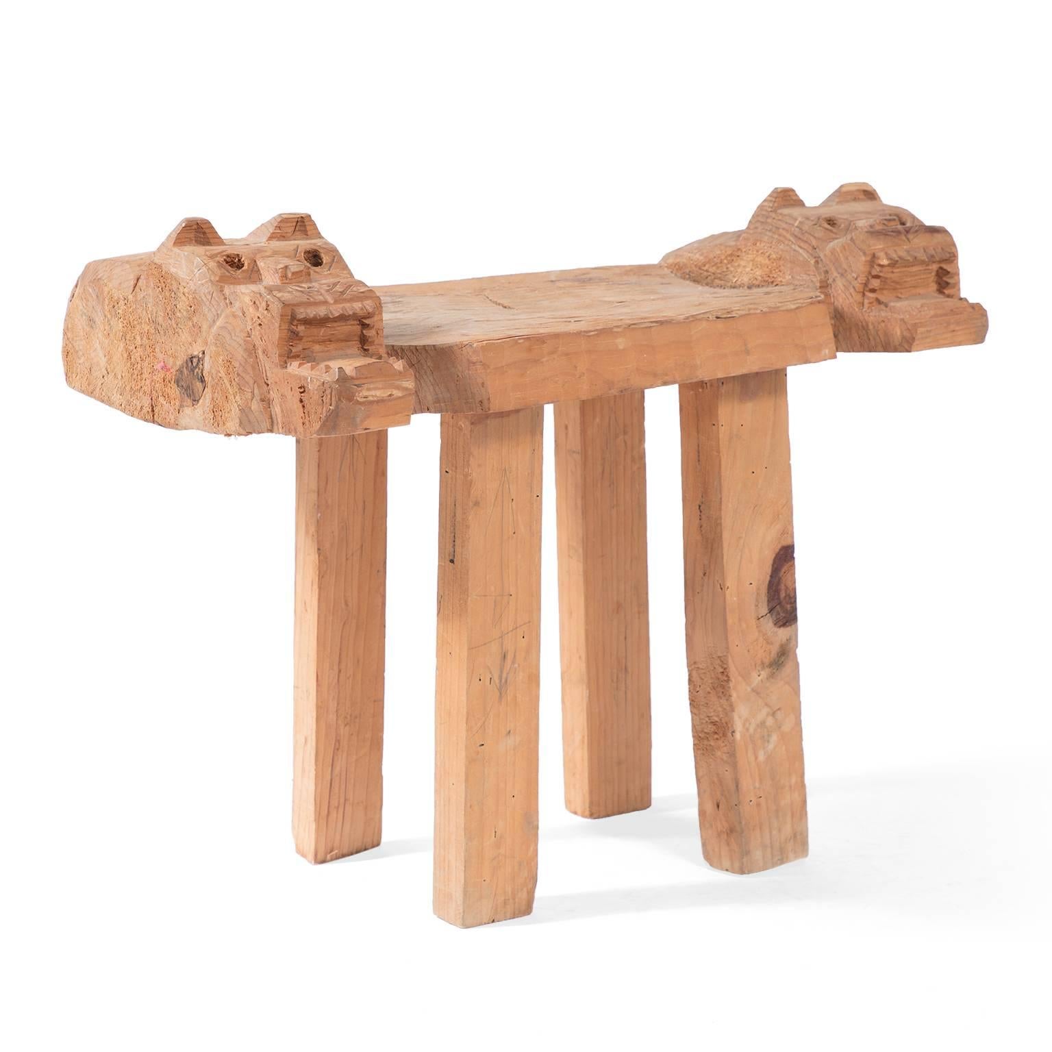 This rustic wood bench was crafted in a Pre-Columbian Folk Art style, with two jaguar heads on either end. Symbolic of divinity and leadership, each jaguar features individually carved triangular ears, diamond-shaped eyes, incised whiskers and