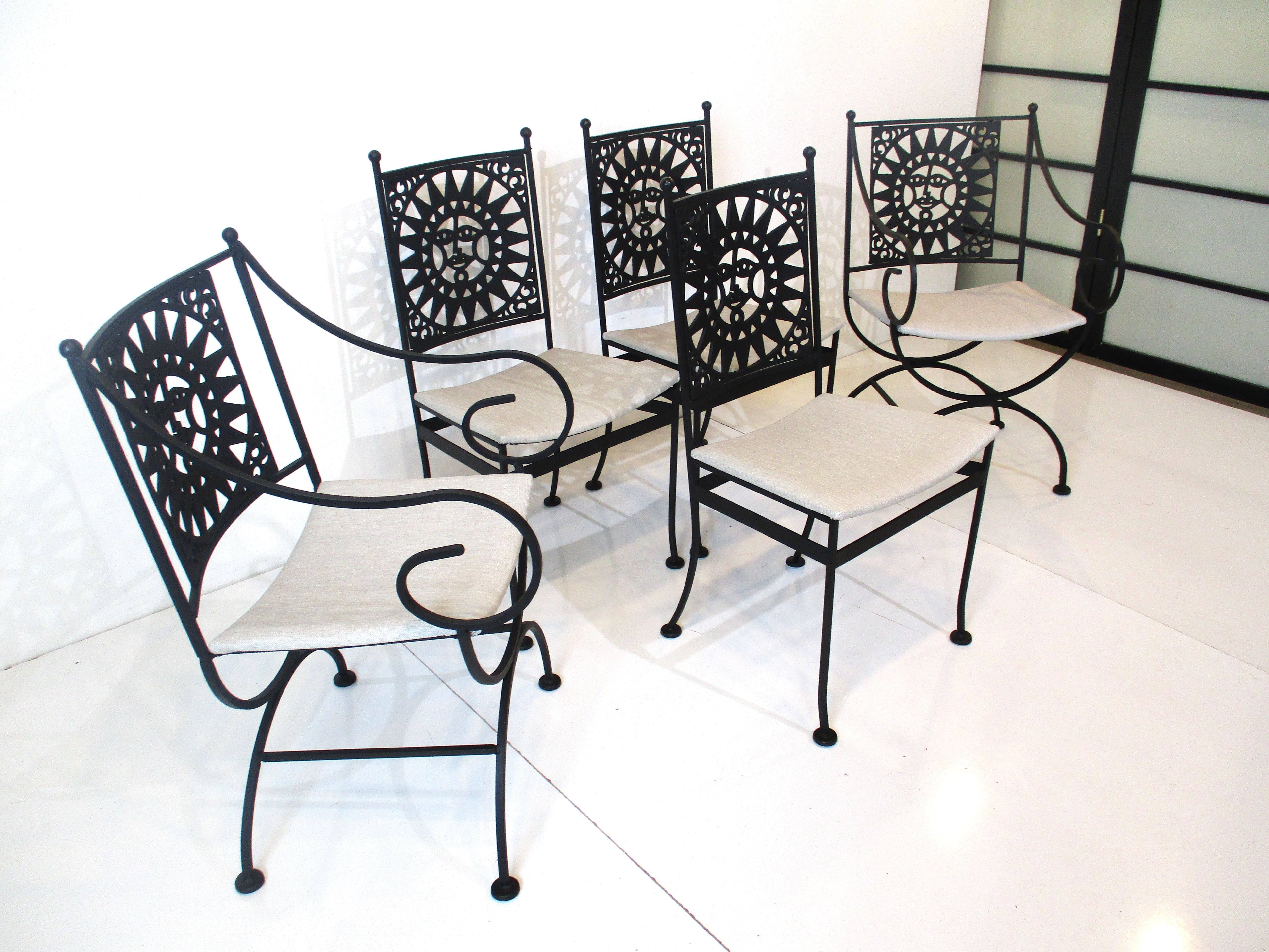 A fine satin black wrought iron dining set with cast Mayan sun design to the chair backs and to the lower center of the table. This sculptural set is very well crafted with 3 side chairs, 2 head arm chairs with upholstered bottoms and the table with