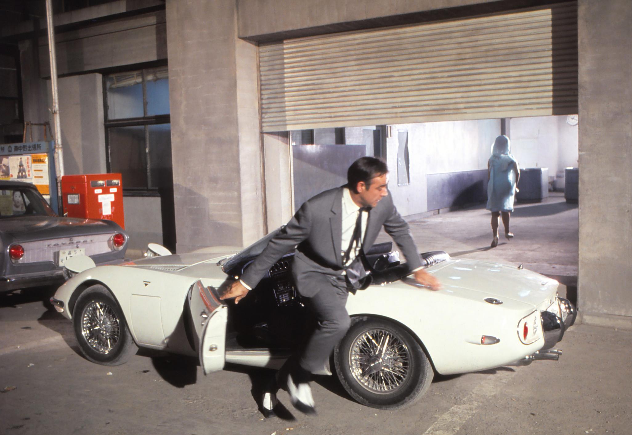 Maynard Frank Wolfe Color Photograph - James Bond Running Beside Car Fine Art Print