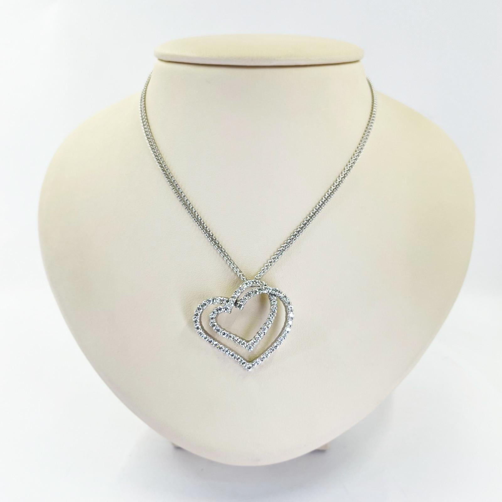 Mayors 18 karat white gold double heart pendant necklace featuring 67 round brilliant cut diamonds of VS clarity and G color totaling 2.00 carats. Pendant slides on a double chain featuring adjustable 16 - 17 inch length with lobster clasp. Finished