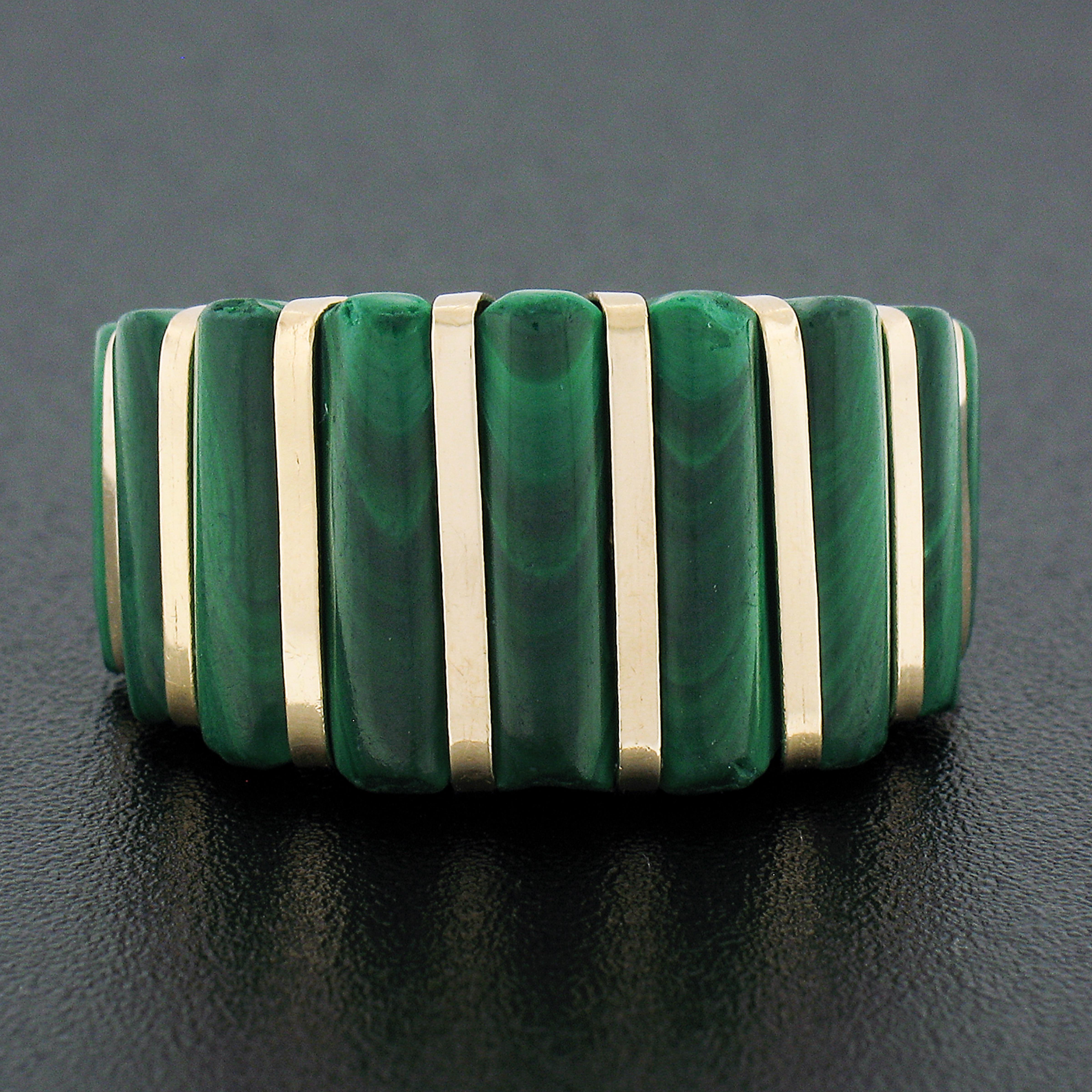 This magnificent statement ring is designed by MAZ and crafted from solid 14k yellow gold. It features a large domed top with a neat and elegant design that is constructed from inlaid set malachite stones and yellow gold stripes, in which slightly