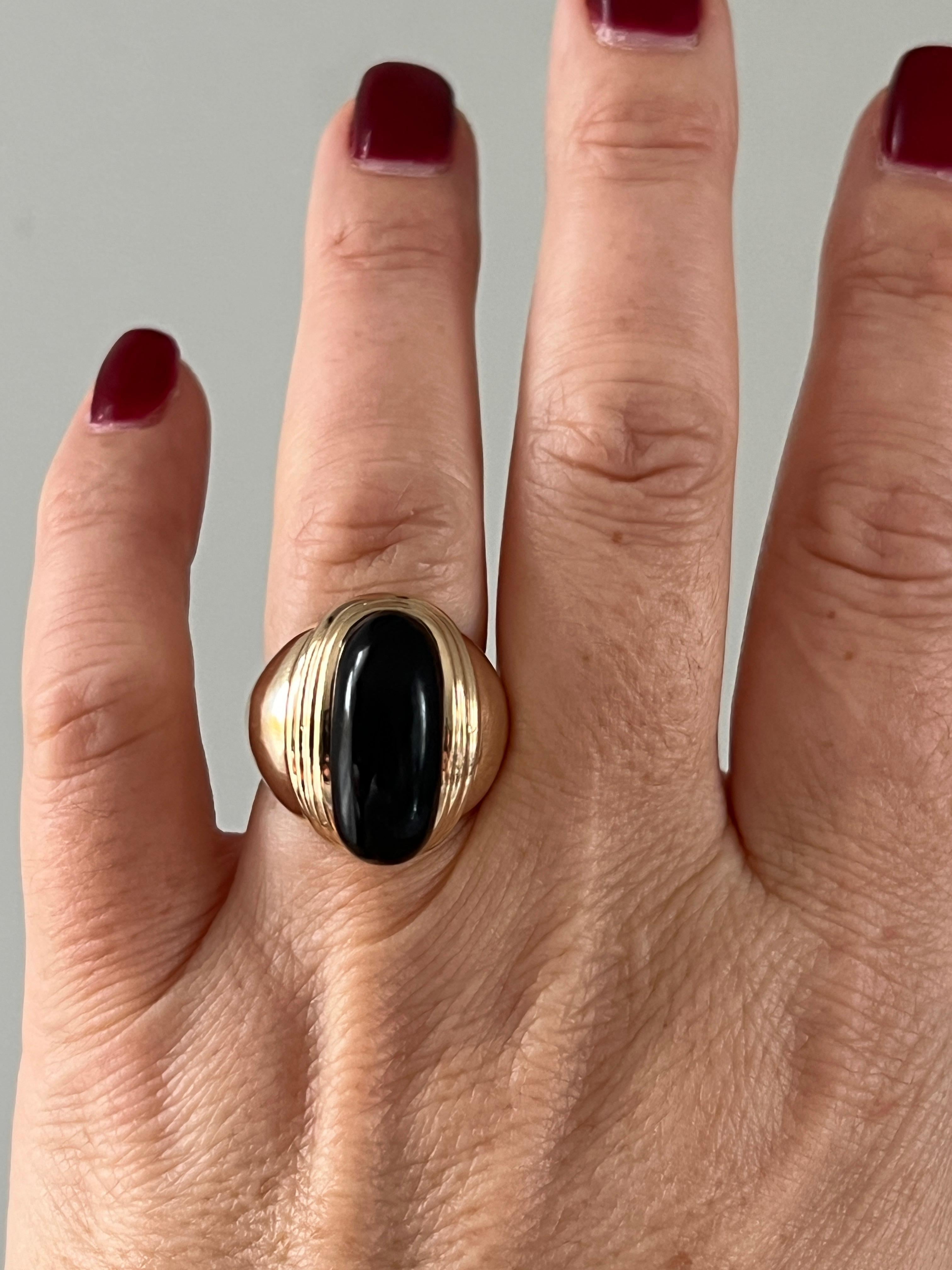 This striking contemporary statement ring by MAZ showcases an elongated oval cabochon onyx, set in rich 14K yellow gold. The bold design features a distinctive ribbed pattern that flows seamlessly into a tapered shank, measuring 20.91mm at its