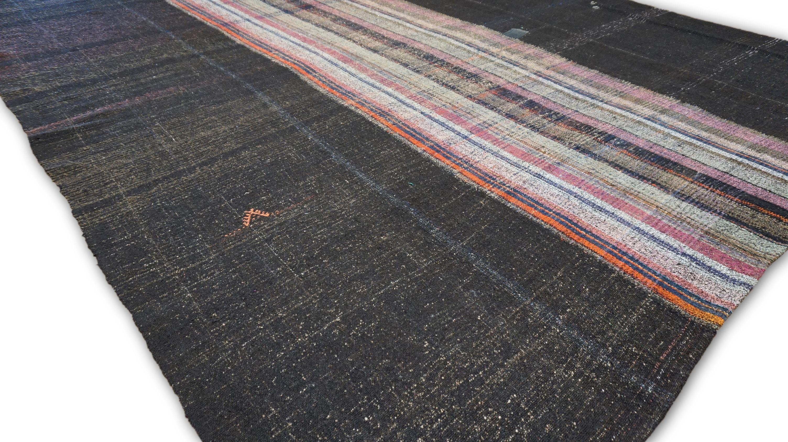 Questo kilim di lana vintage è uno splendido esempio di artigianato tradizionale, caratterizzato da un design audace con pannelli a righe e a tinta unita con accenti rosa, viola, grigi e marroni. La sezione centrale è caratterizzata da vivaci